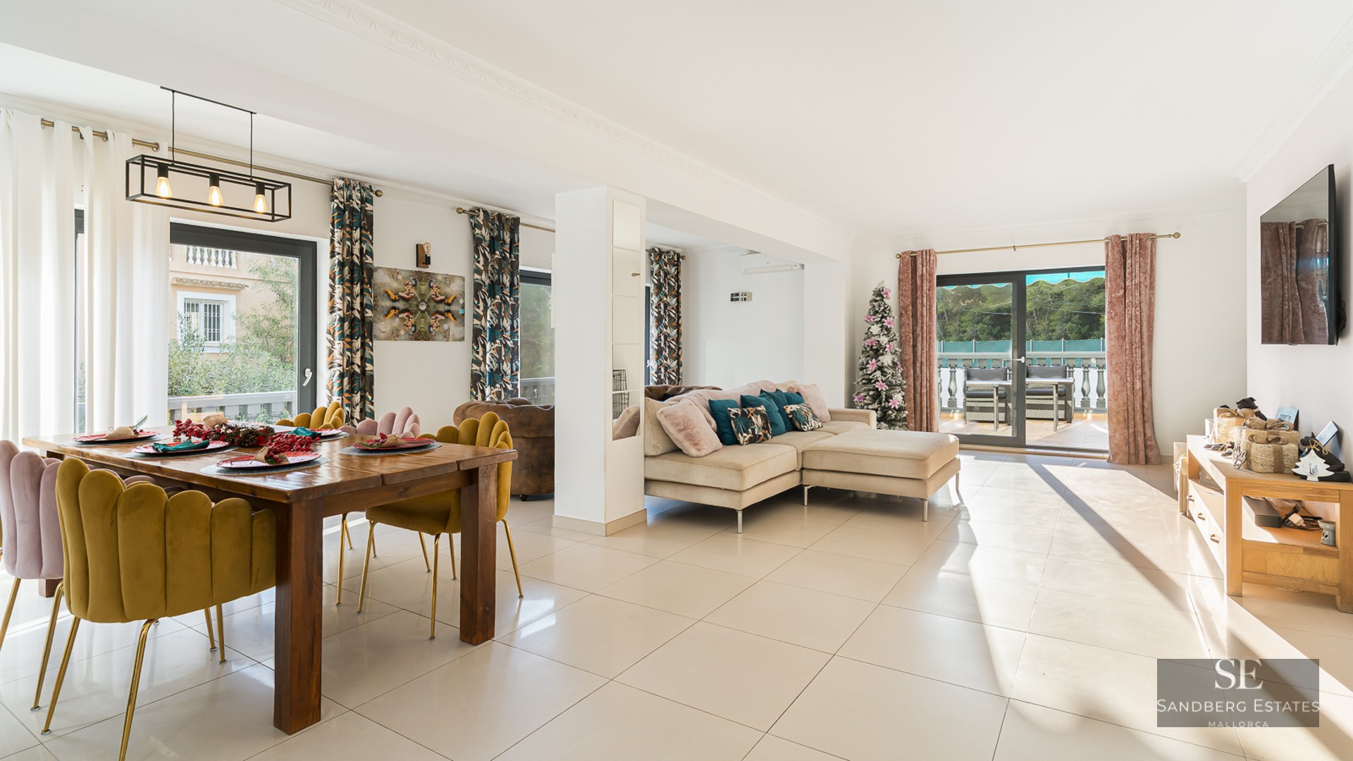 Espace de vie lumineux avec chaises en velours moutarde, canapé beige et grandes baies vitrées ouvrant sur une terrasse.