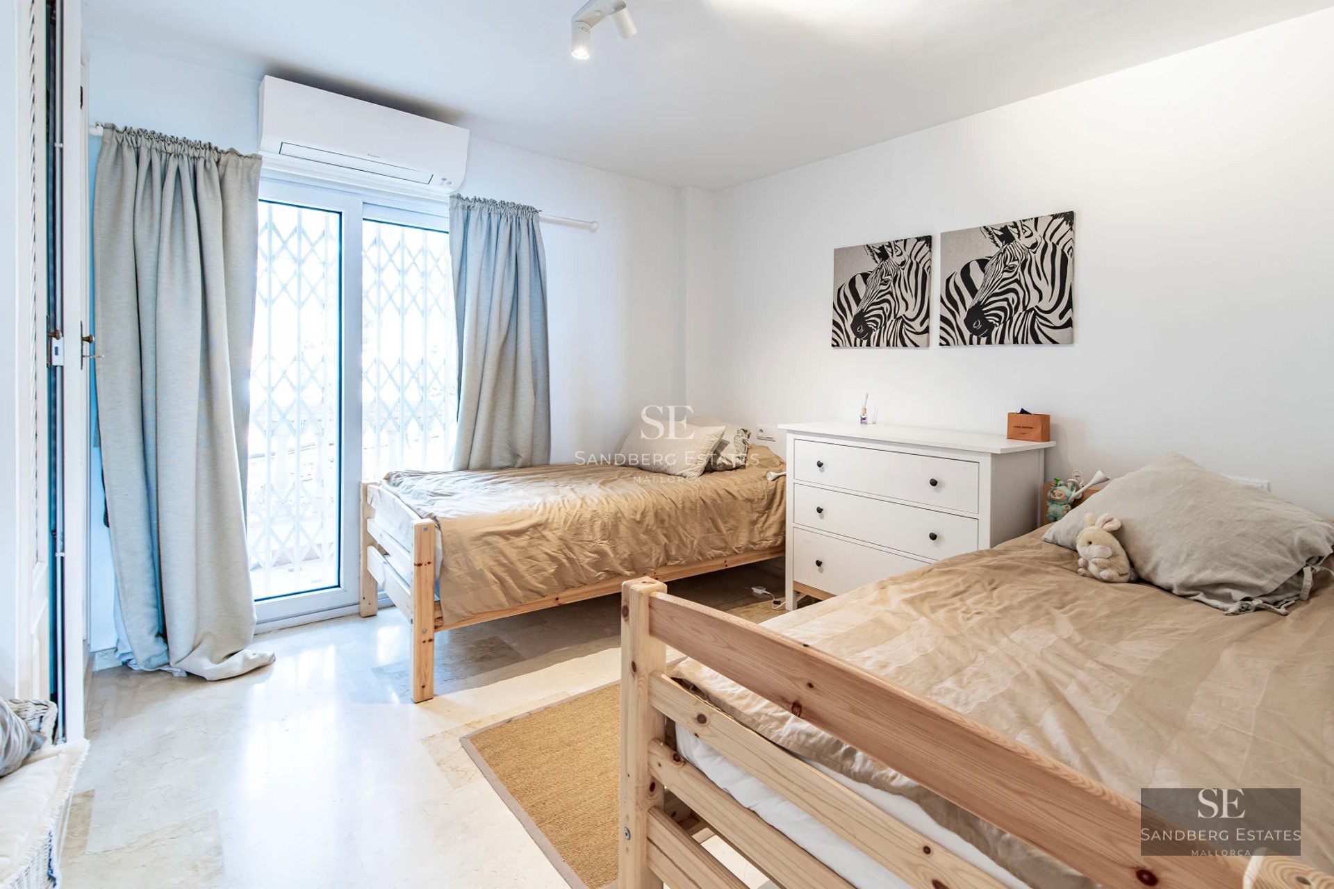 Spacious living room with panoramic windows, light wood flooring, modern fireplace, and minimalist furniture. Abundant natural lighting.