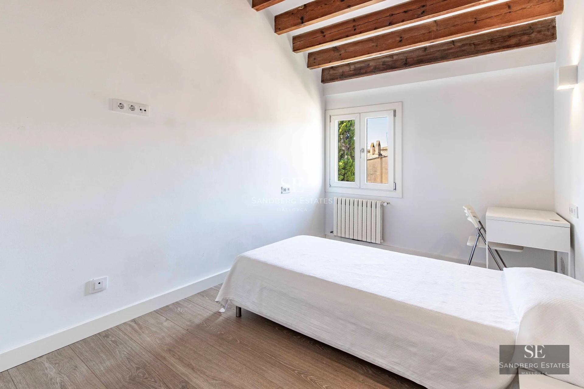 Bright living room with floor-to-ceiling windows, light wood floors, and balcony access with sea views. Modern and elegant decor.