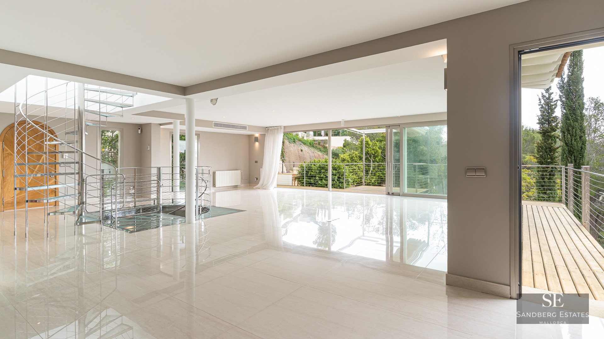 Spacious minimalist room with polished floors, a metal spiral staircase, and large glass doors leading to a terrace.