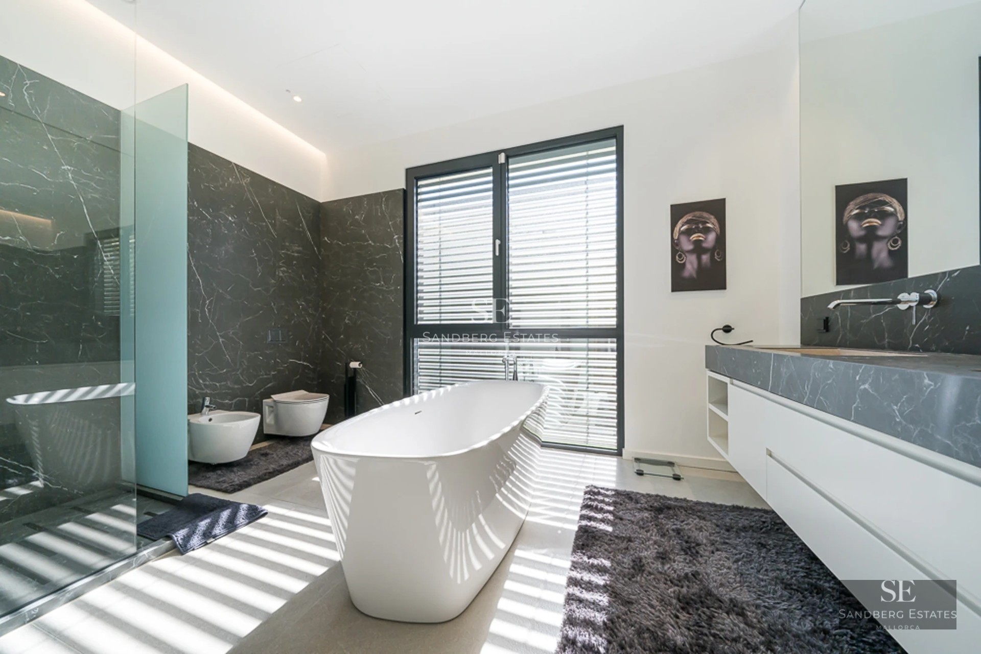 View of villa with infinity pool, sun loungers, and lush vegetation. Modern design with large windows and light colors.