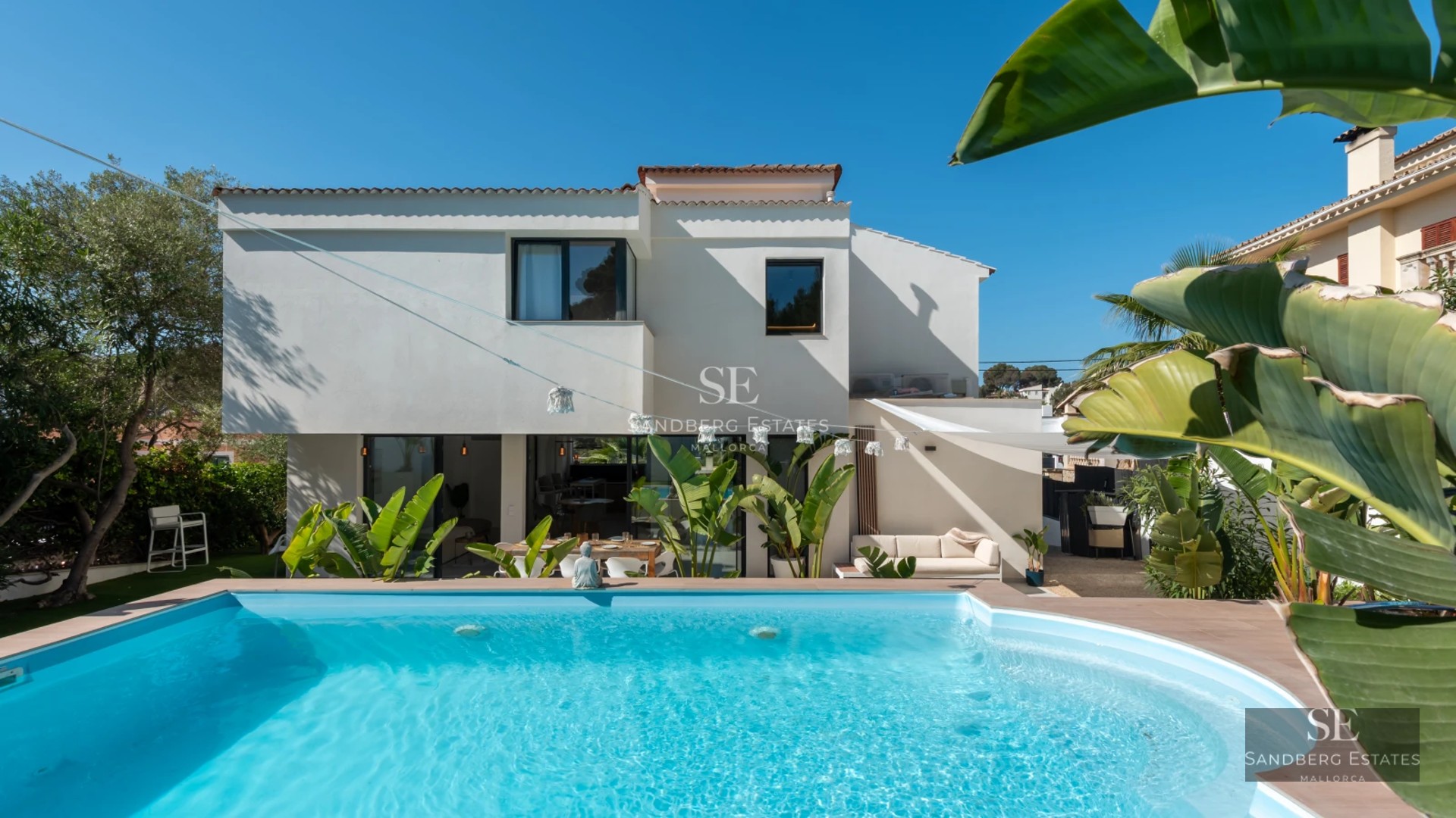 Exterior view of a luxurious modern house with a pool, garden, and large windows. Contemporary architectural design.