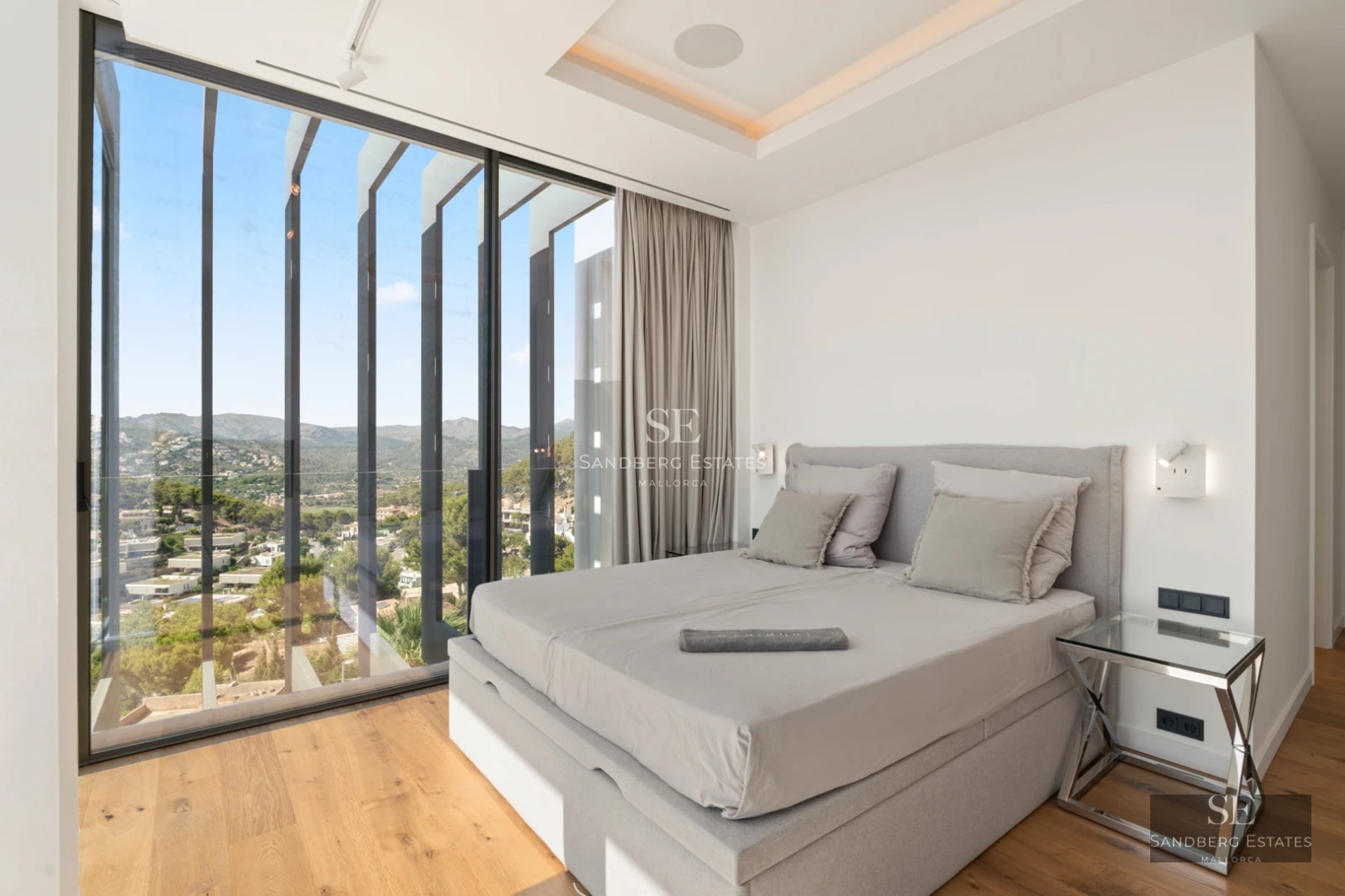 Spacious living room with panoramic windows, natural light, light wood floors, and contemporary furniture. View of the lush garden.
