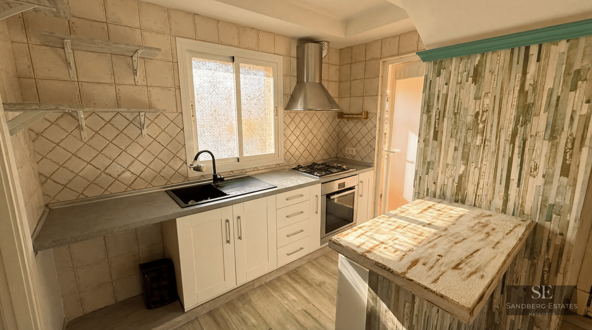 A kitchen featuring white cabinets, a gray countertop, a gas stove, and a rustic wood-finished breakfast bar.