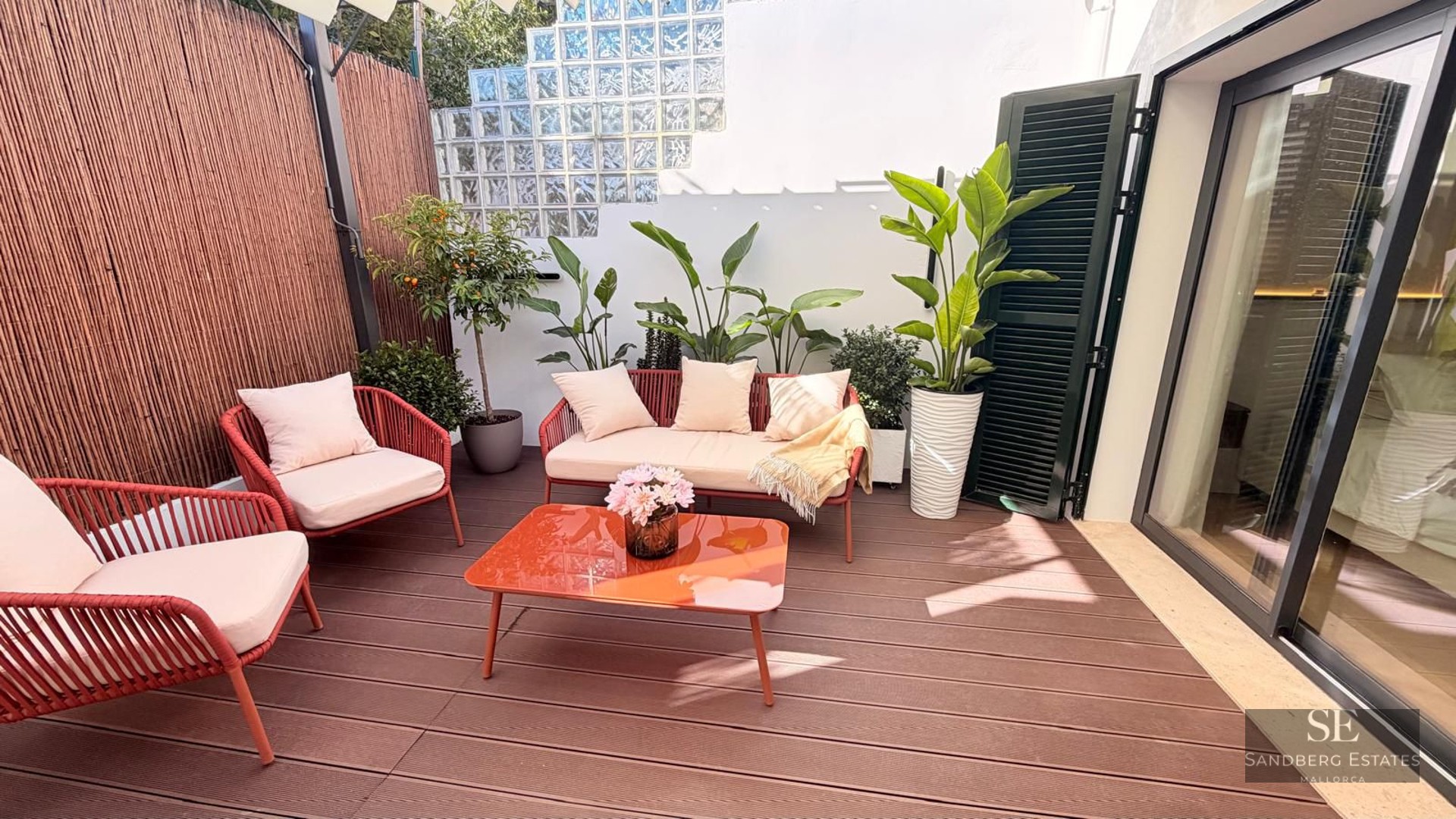 Terrace featuring wood decking, terracotta-colored outdoor furniture, and decorative plants under bright natural light.