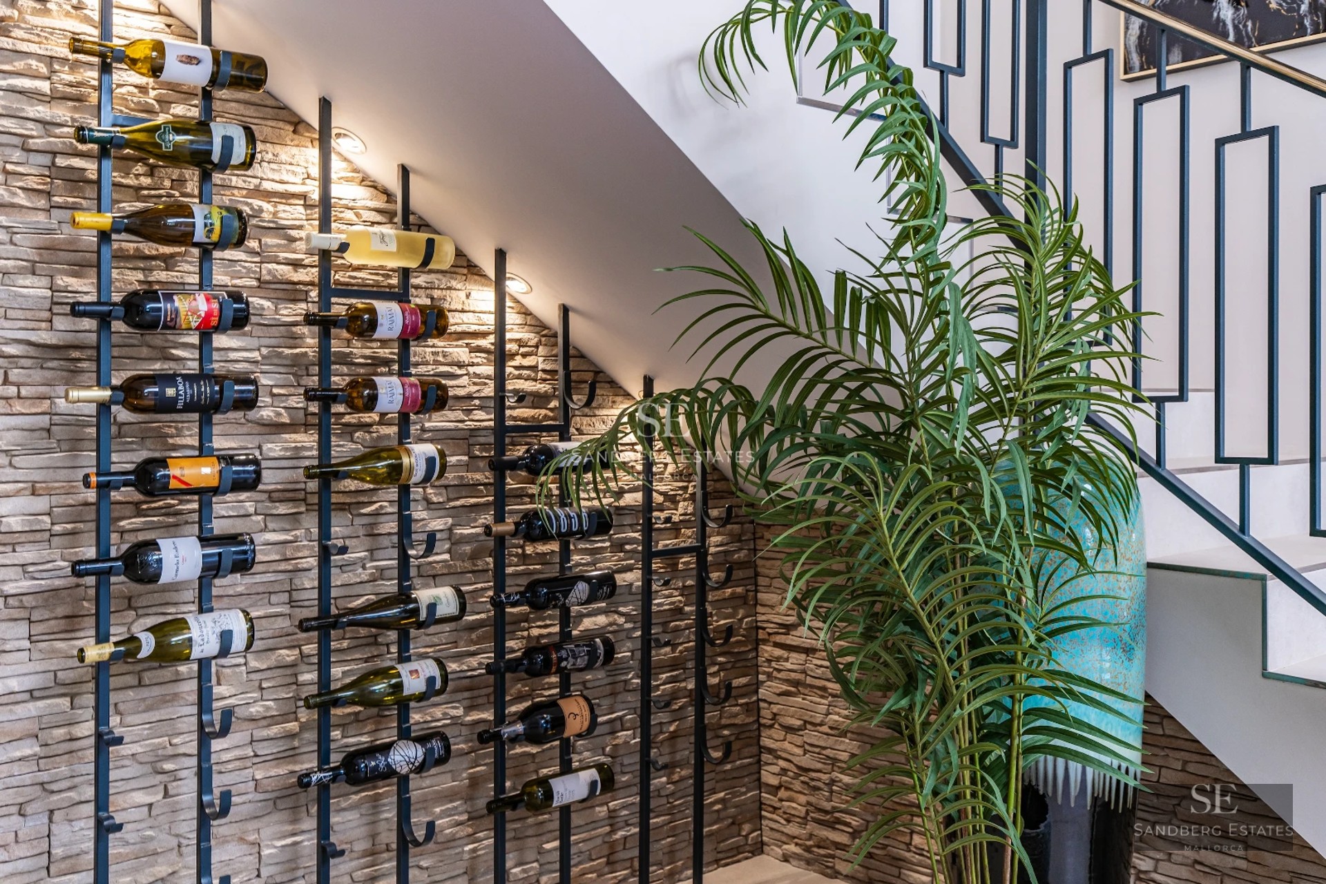 View of infinity pool with sun deck, lounge chairs, and palm trees. Modern architecture, large windows. Natural lighting.