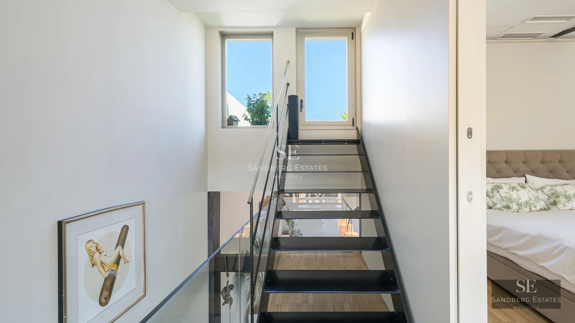 Spacious living room with panoramic windows, light wood floors, modern furniture, and abundant natural light. View of garden and pool.