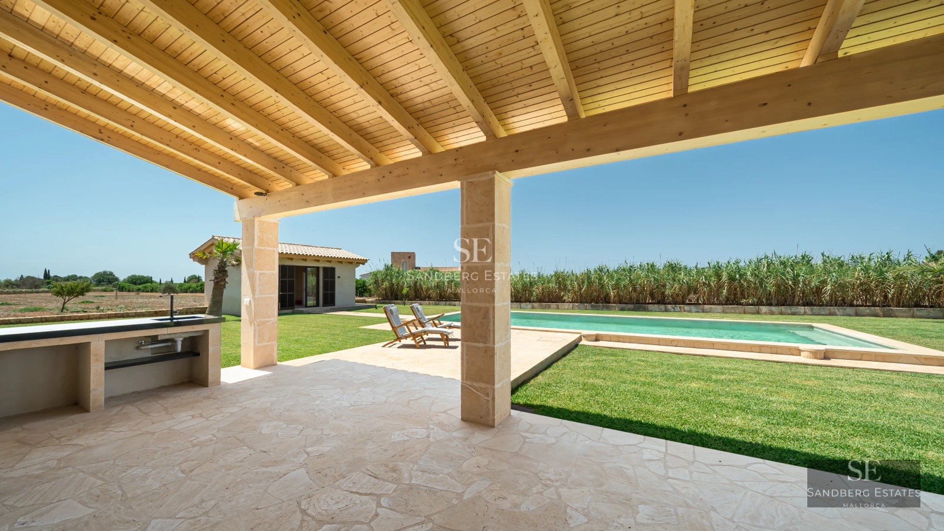 Spacious terrace with infinity pool, sun loungers, and sea view. Modern design with glass windows and lush vegetation.