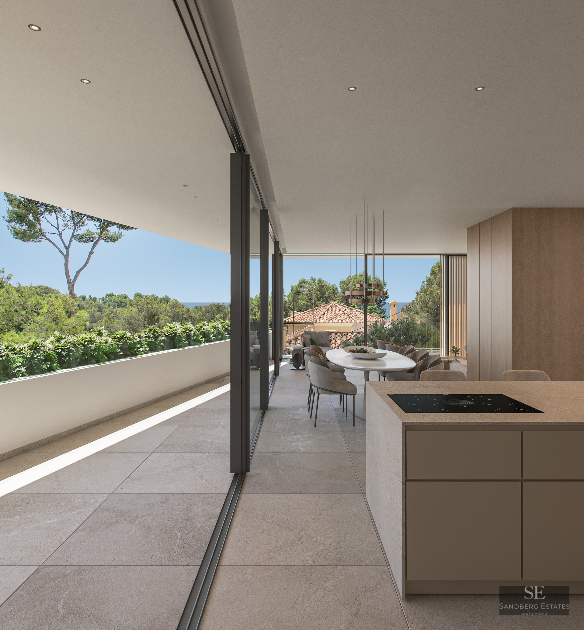 Modern open-plan dining room with stone floors, kitchen island, and glass doors opening to a lush terrace and sea view.
