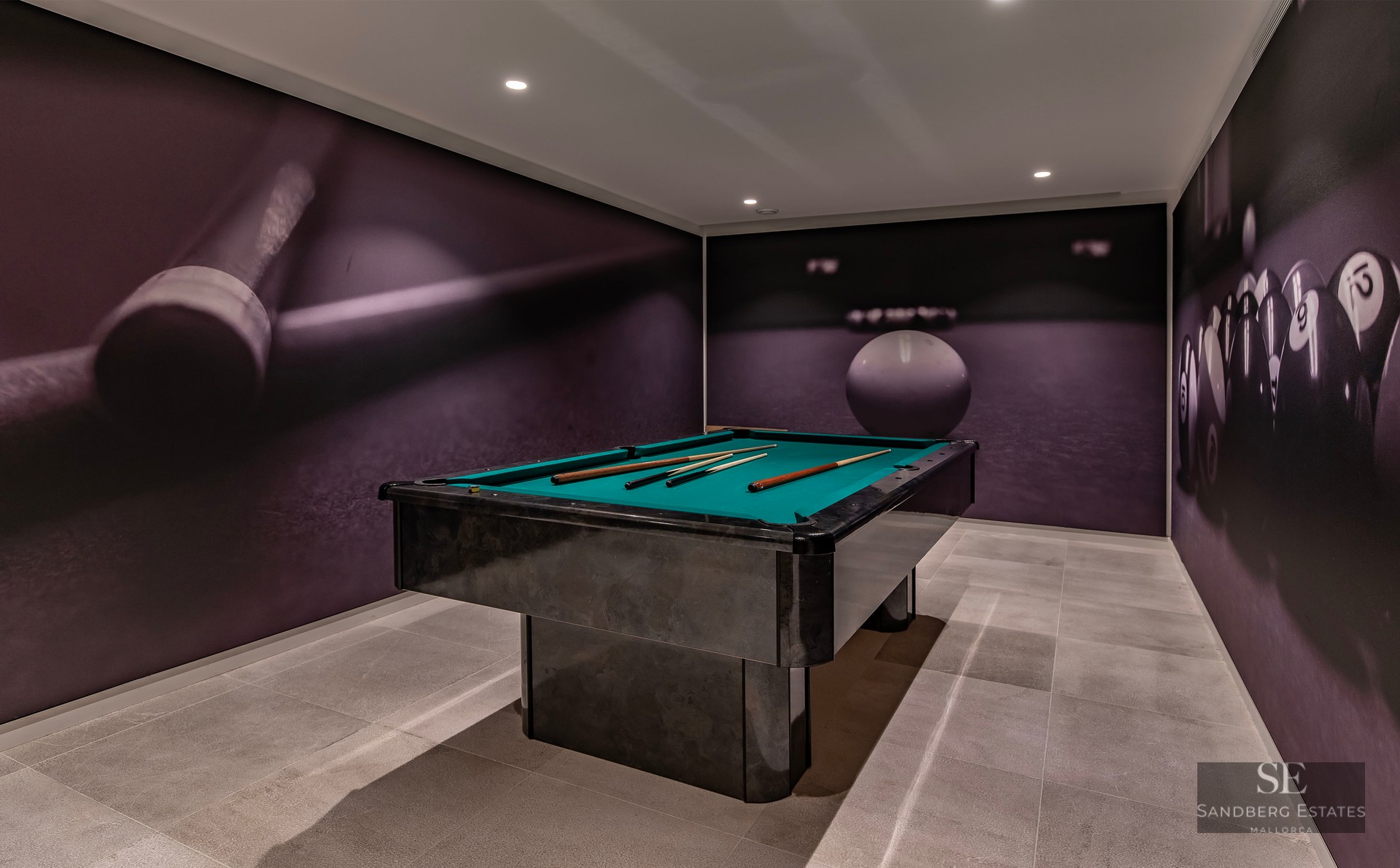 Modern game room featuring a black pool table with green felt and large pool-themed wall murals.