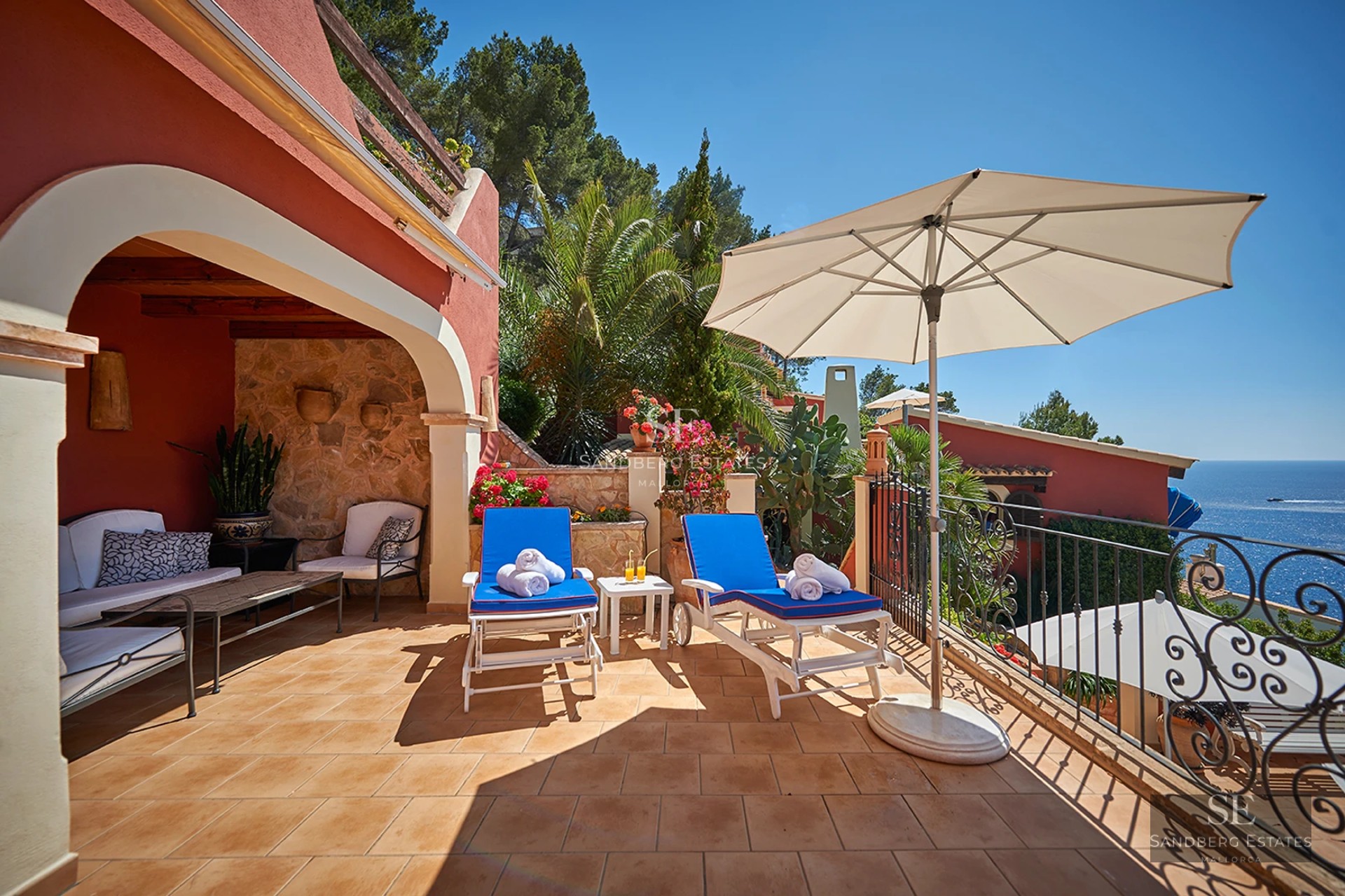 View of a modern villa featuring an infinity pool, expansive terraces, and lush gardens. Minimalist design with large windows.