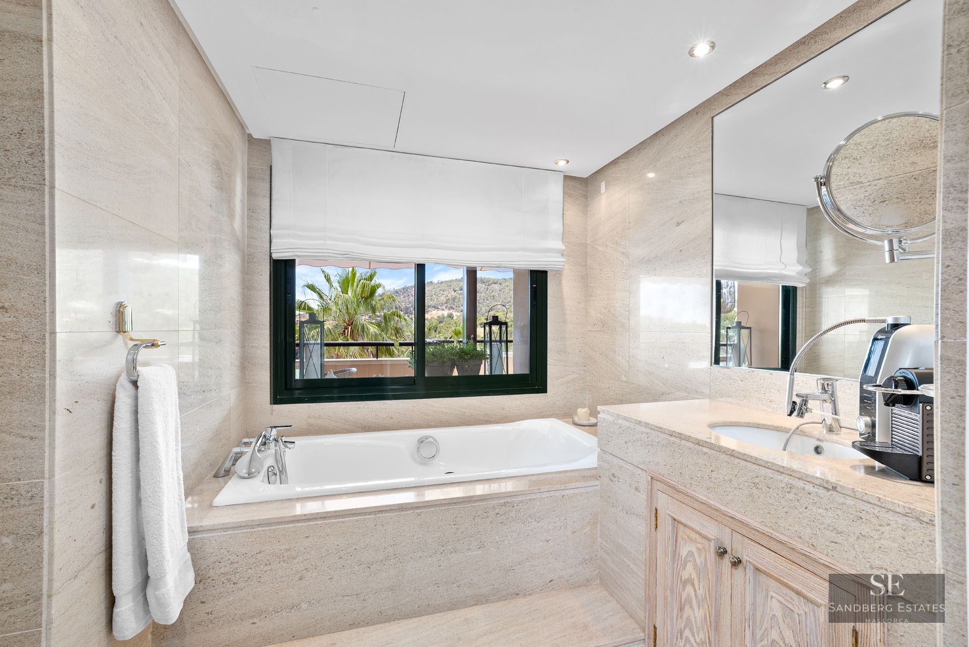 Salle de bain principale élégante avec baignoire en pierre, grande fenêtre avec vue et vasque en marbre.