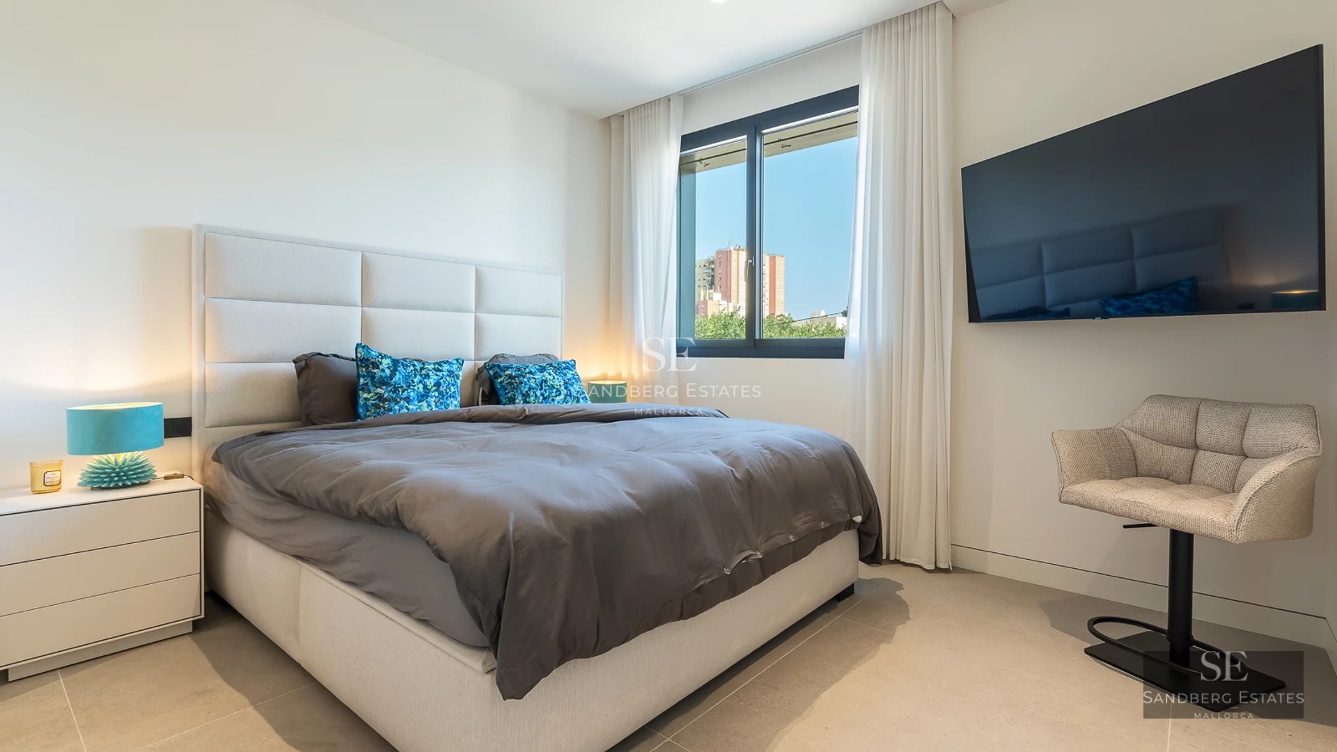 Aerial view of infinity pool surrounded by lawn and sun loungers. Modern house with panoramic windows and covered terrace.