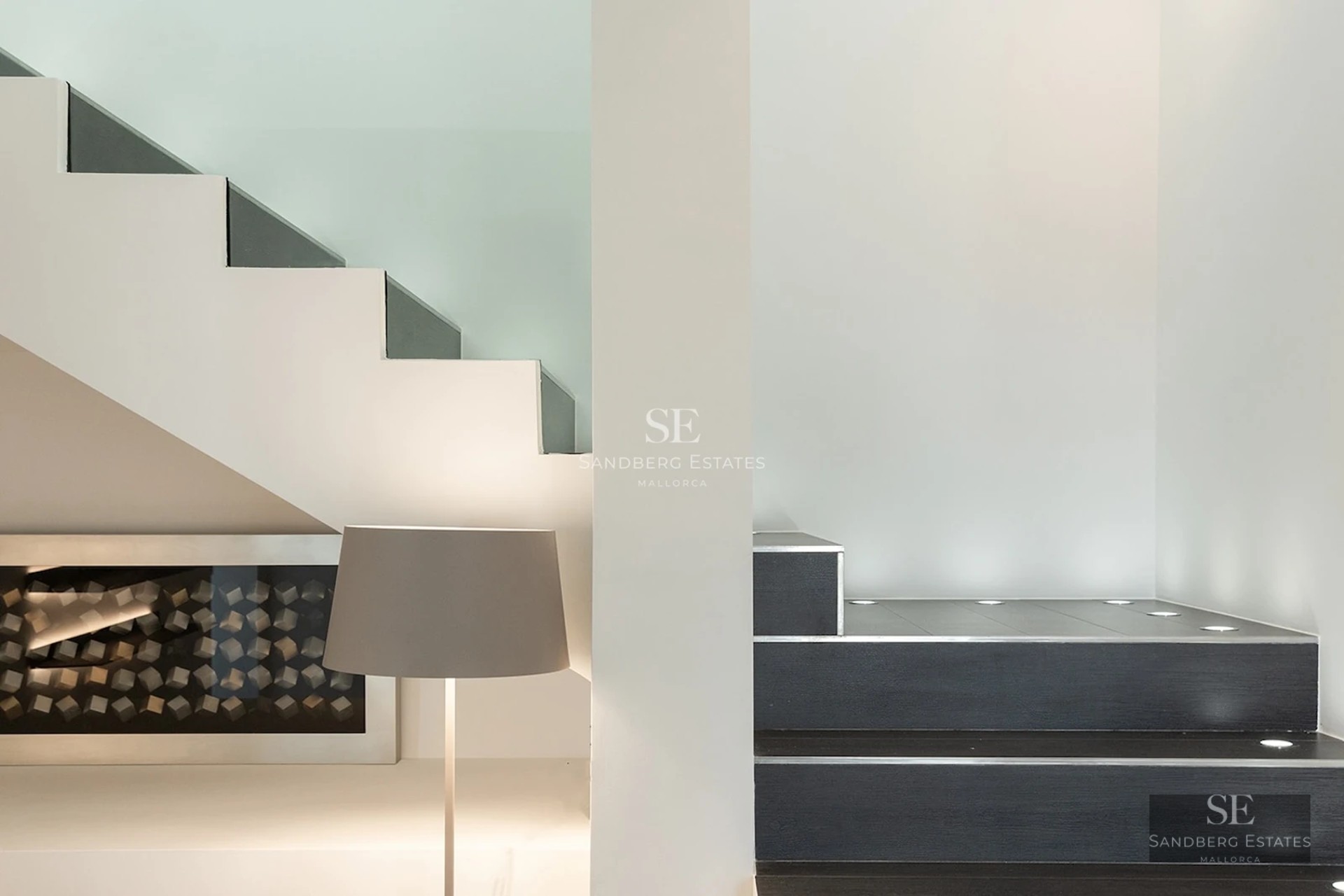 A modern interior featuring dark steps with built-in LED lights next to a glass-enclosed wine storage unit.