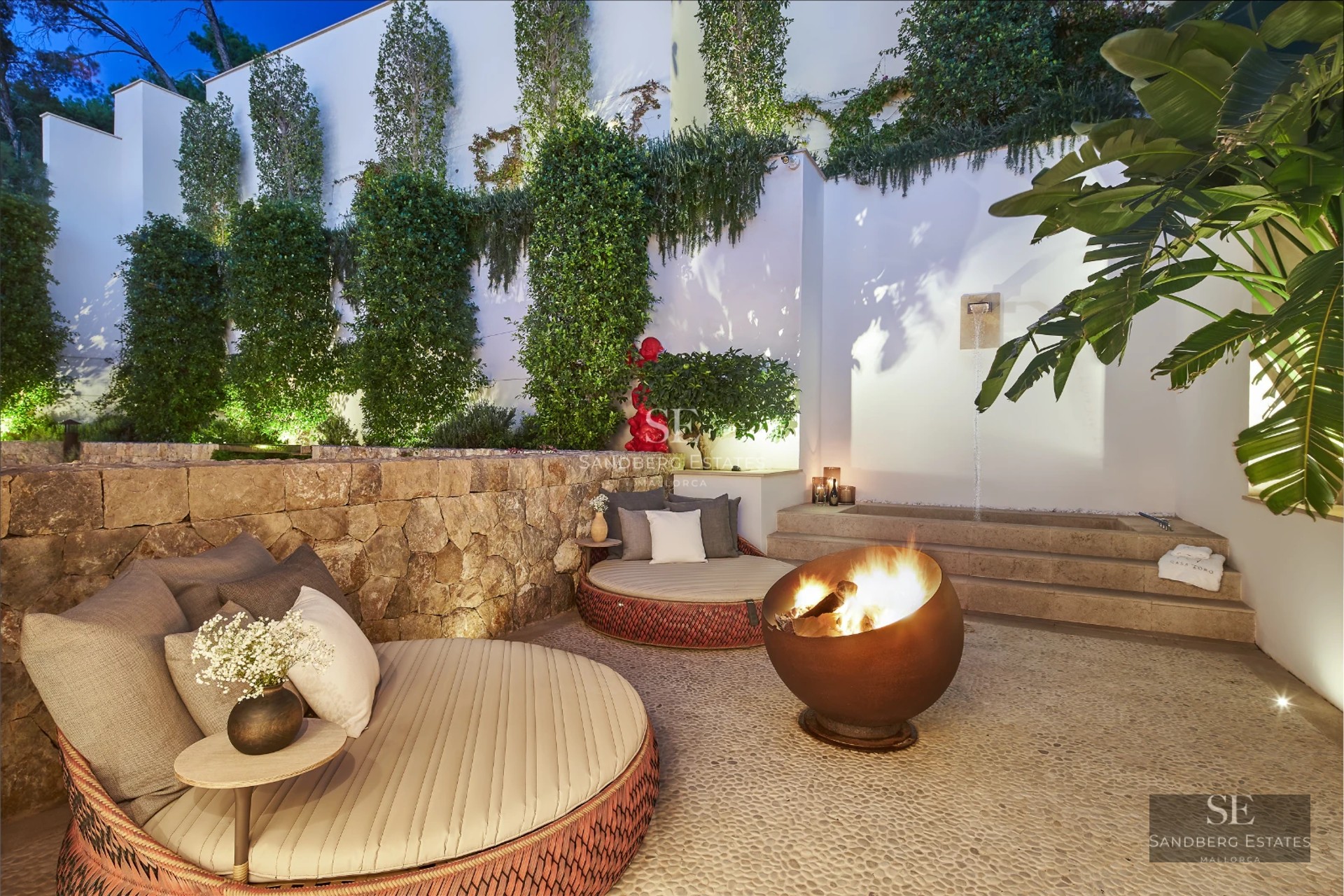 Spacious living room with fireplace, picture windows, and designer furniture. Warm, natural lighting. Wooden floors and light walls.