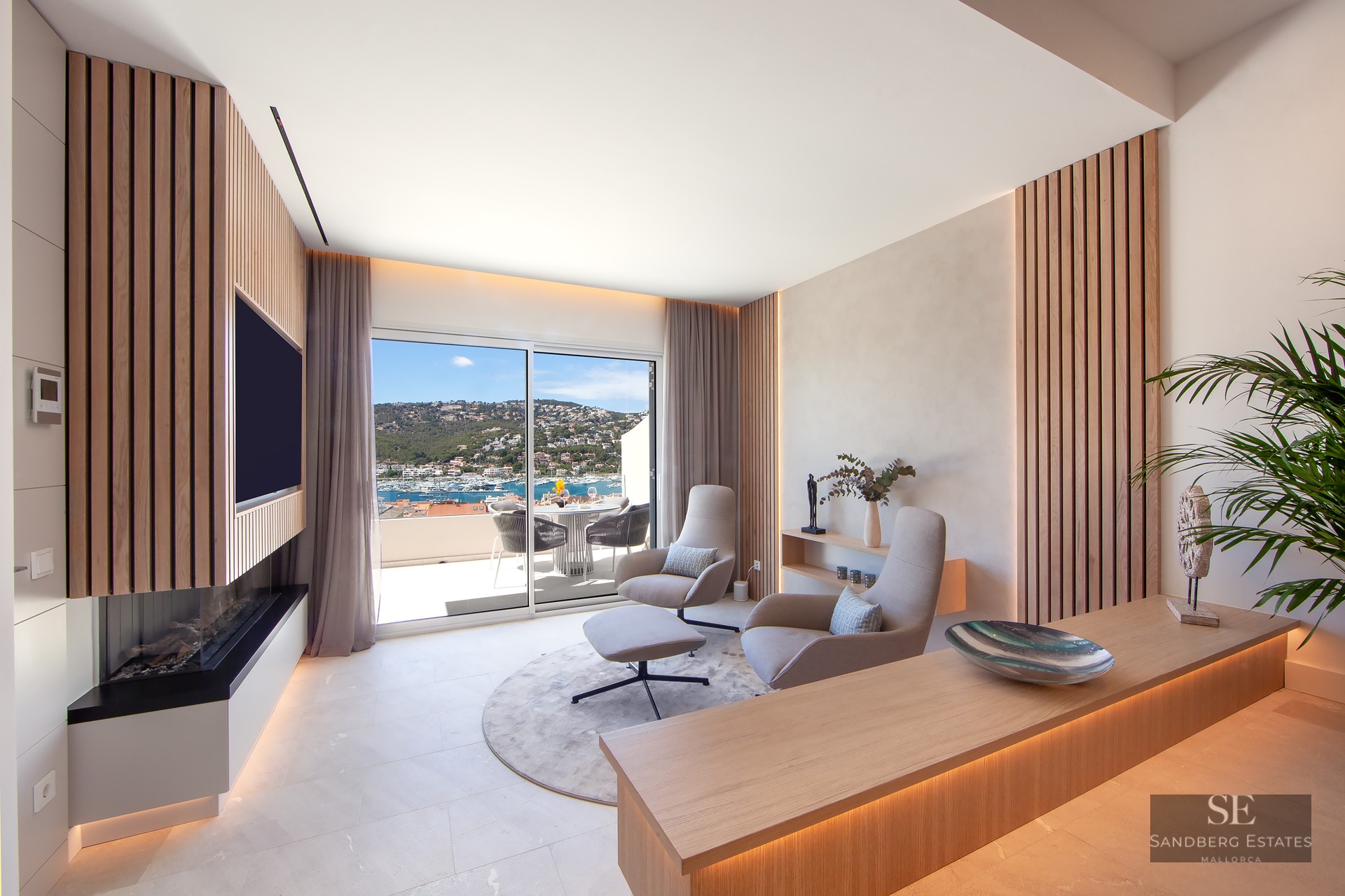 Modern lounge with wood slats, designer chairs, and a sliding glass door revealing a stunning Mediterranean harbor view.