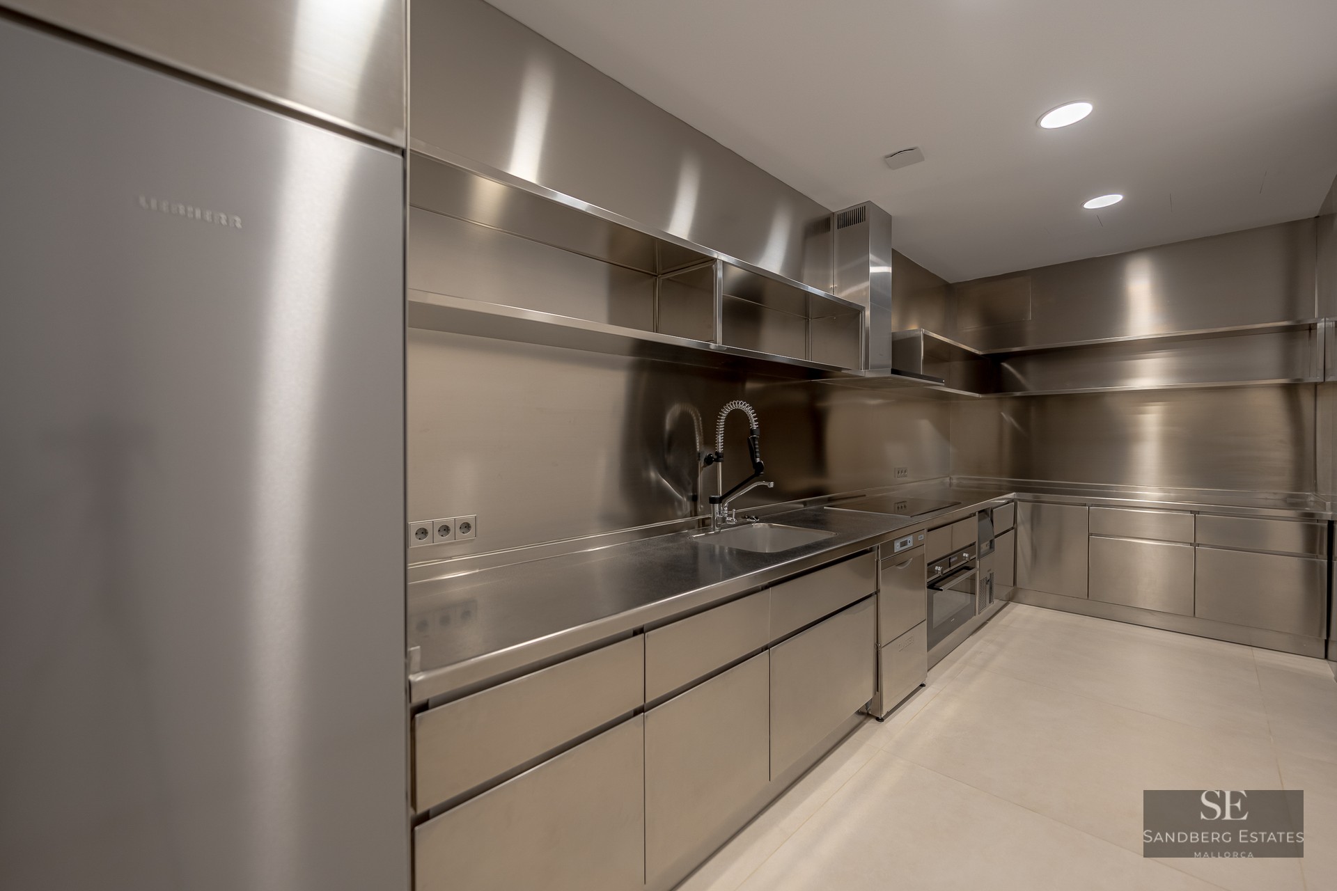 Modern industrial kitchen featuring high-end stainless steel cabinets, countertops, and a professional-grade faucet.