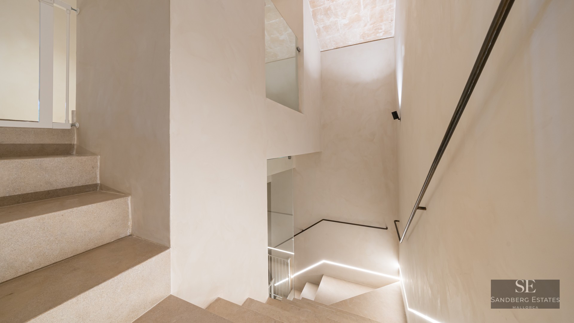 Minimalist design stone staircase with a slim metal handrail and integrated LED floor lighting.