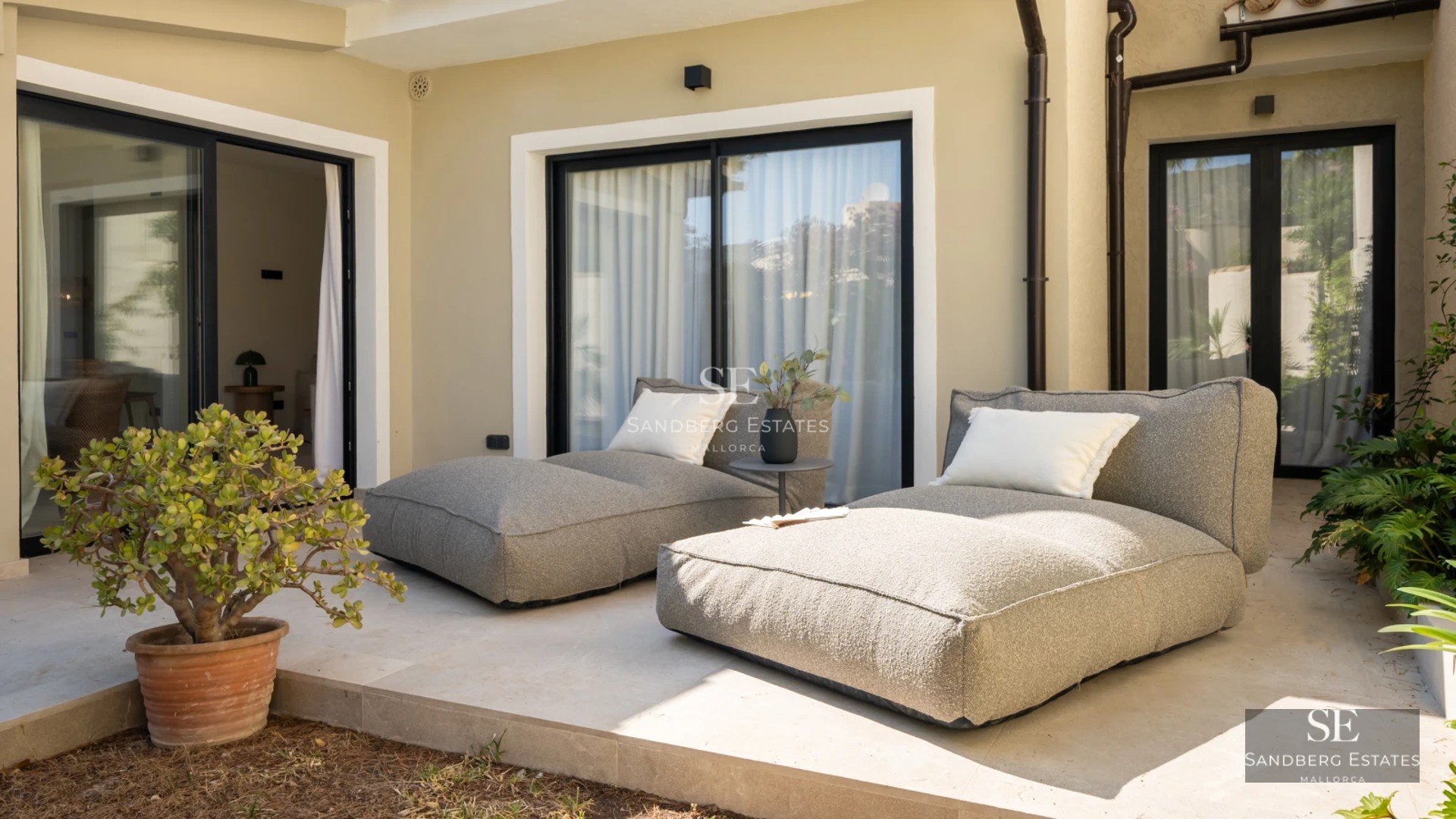 Spacious balcony with sea views, glass railing, modern furniture, and light wood floors. Warm ambient lighting.