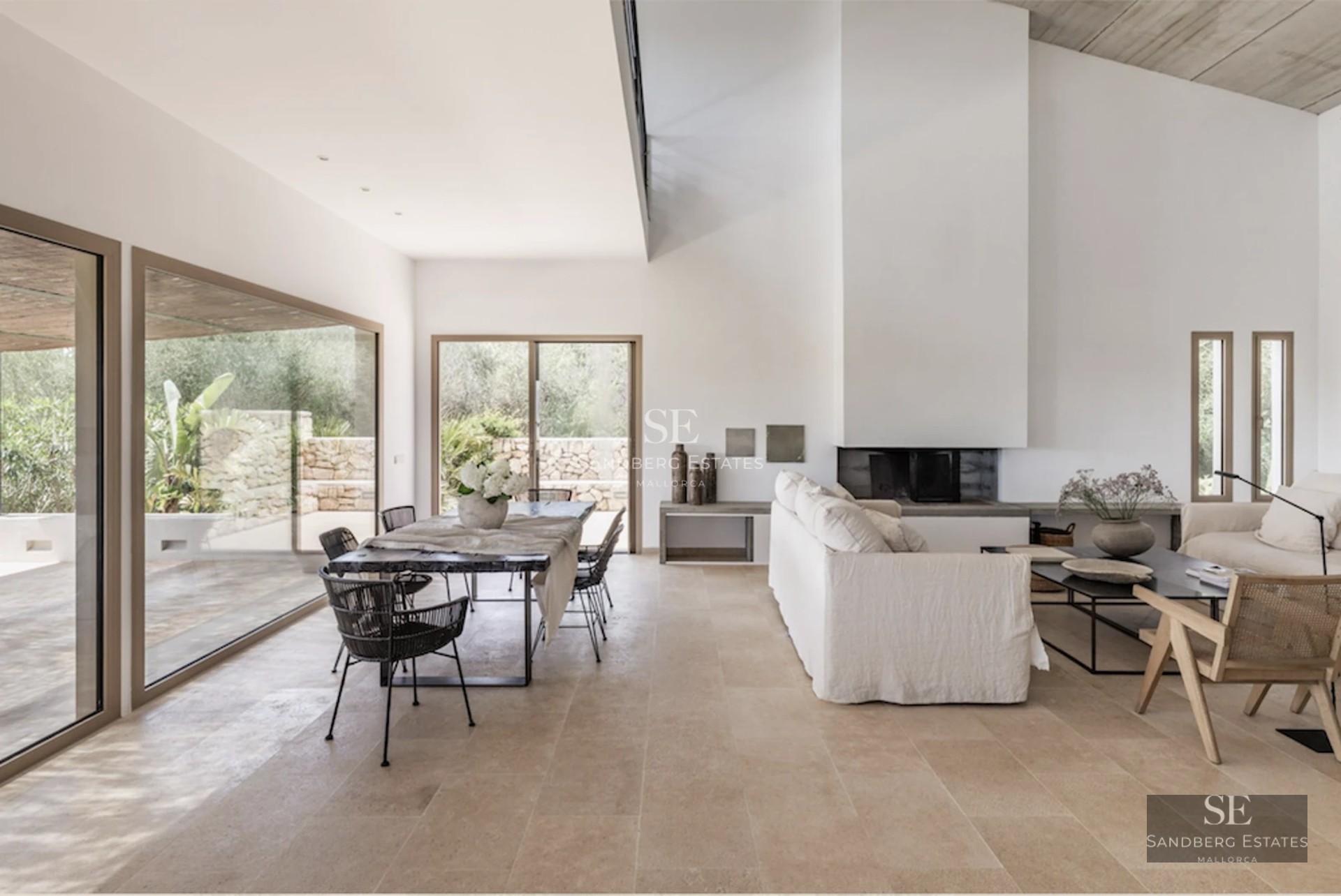 View of a luxury villa featuring an infinity pool, surrounded by lush gardens and expansive terraces. Modern design with window walls and natural stone.