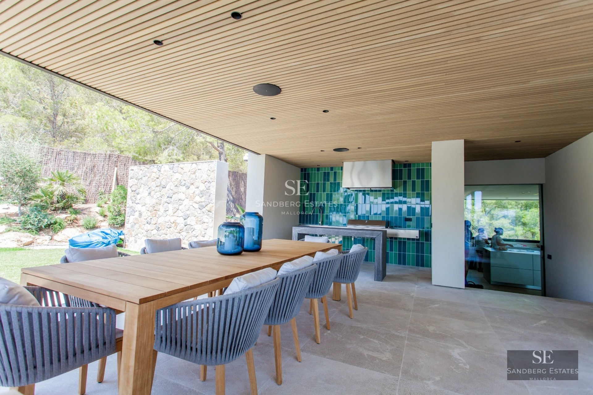 Panoramic view of a modern living room with a balcony, stylish furniture, wooden floors, and large windows offering stunning sea views.