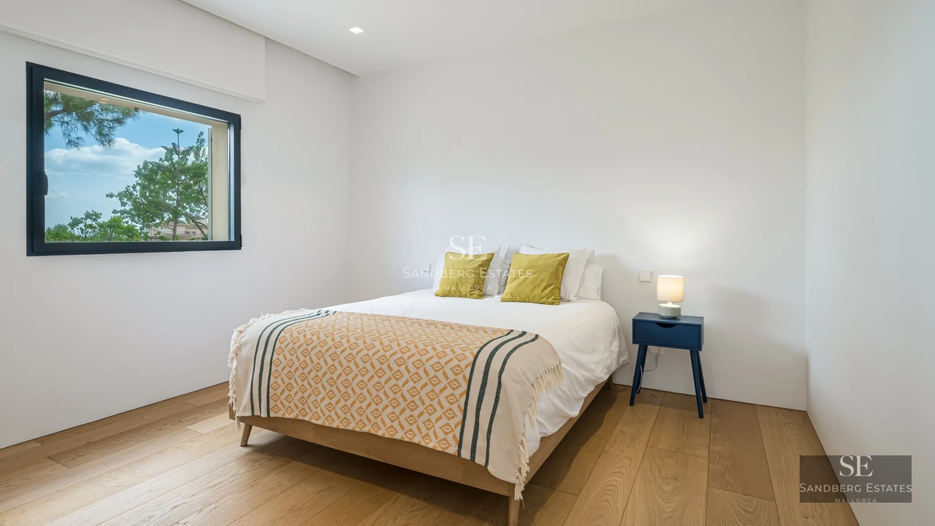 Spacious living room with floor-to-ceiling windows, wood floors, modern furniture and balcony access. Natural light and panoramic views.