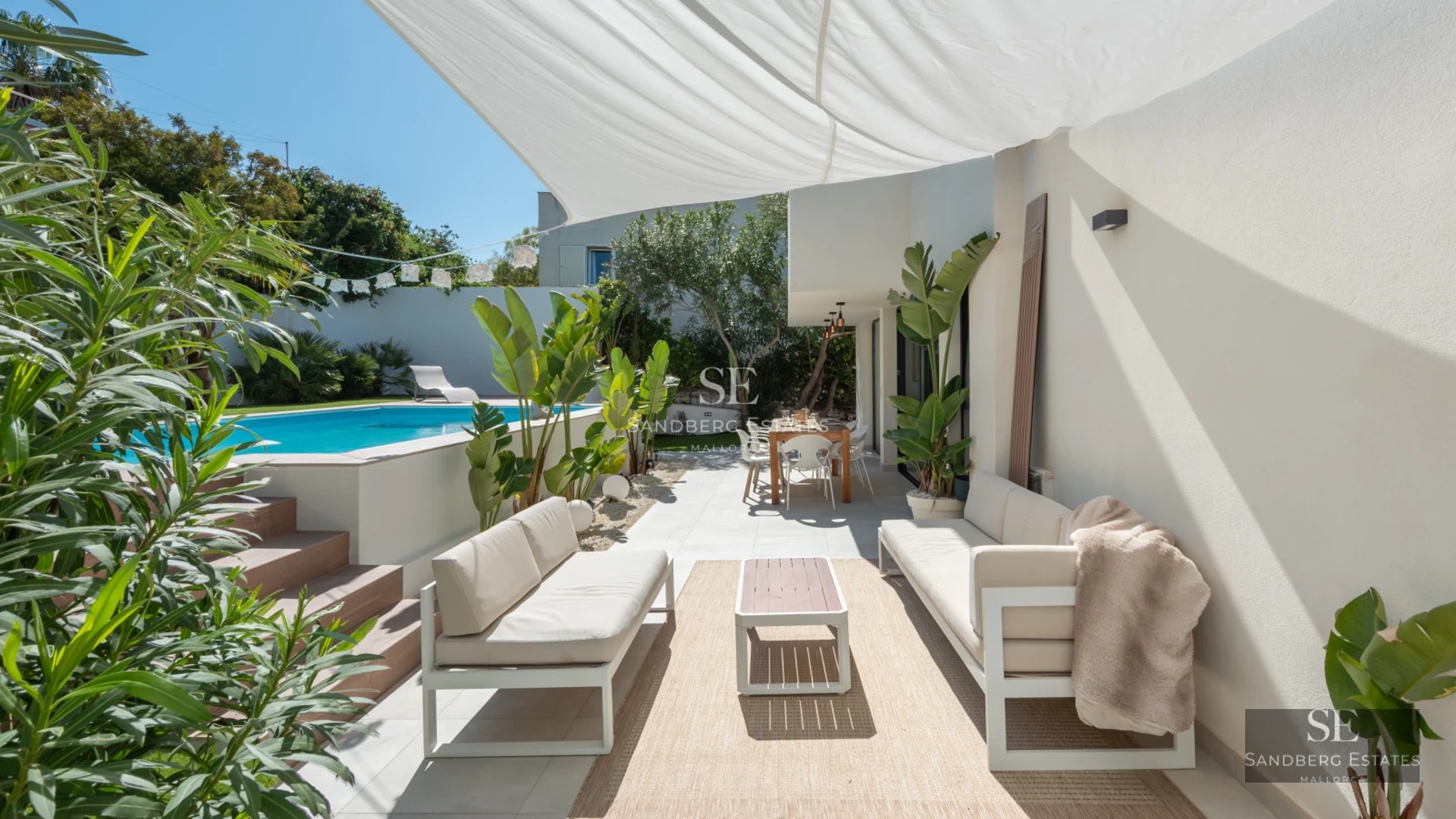 Panoramic view of a modern villa featuring an infinity pool, wooden deck, and lush garden. Elegant architecture and high-quality finishes.