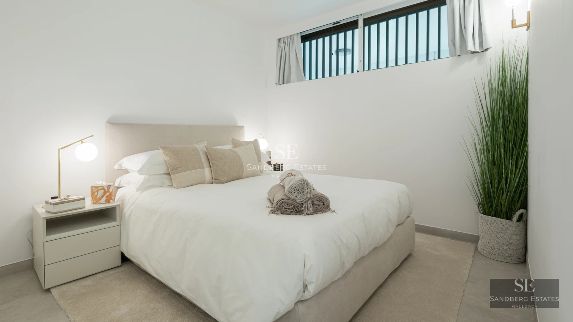 Panoramic view from a balcony featuring wood flooring, glass railing and modern furniture overlooking the sea. Natural lighting.