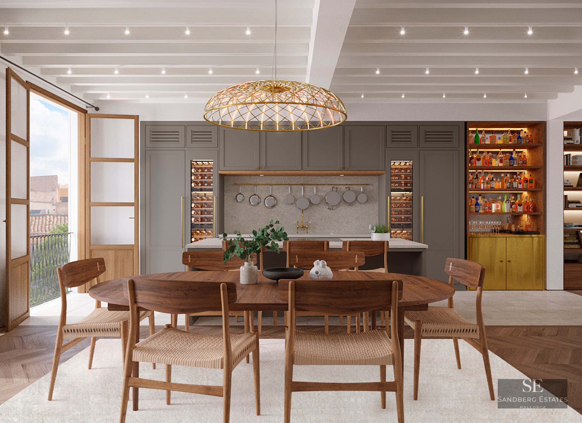 Elegant dining room with a wooden table, woven chairs, a large gold pendant light, and a modern kitchen with wine fridges.