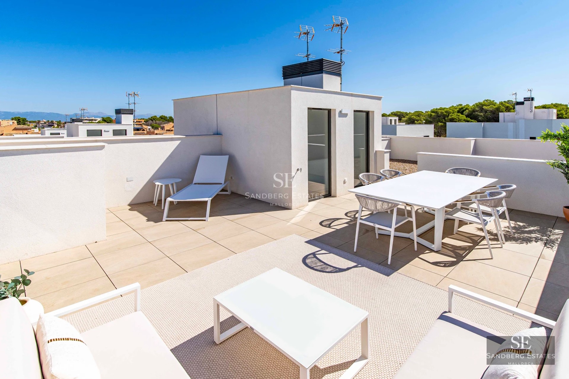 Spacious terrace with wooden flooring, glass railing, panoramic sea view, and modern outdoor furniture. Natural lighting.
