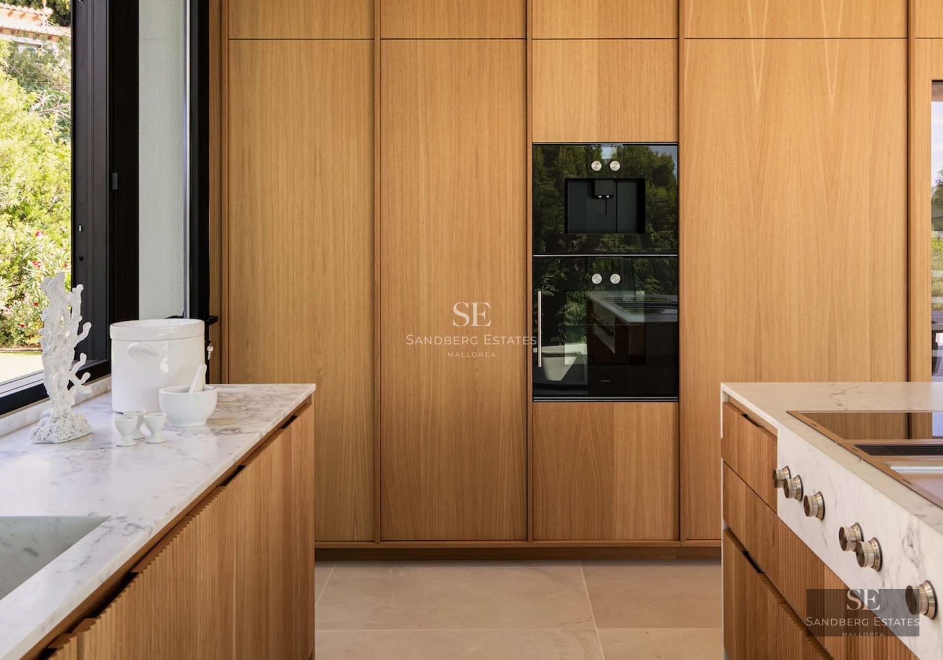 View of a modern villa with an infinity pool, wooden terrace, and large windows overlooking the sea. Minimalist design with high-end finishes.