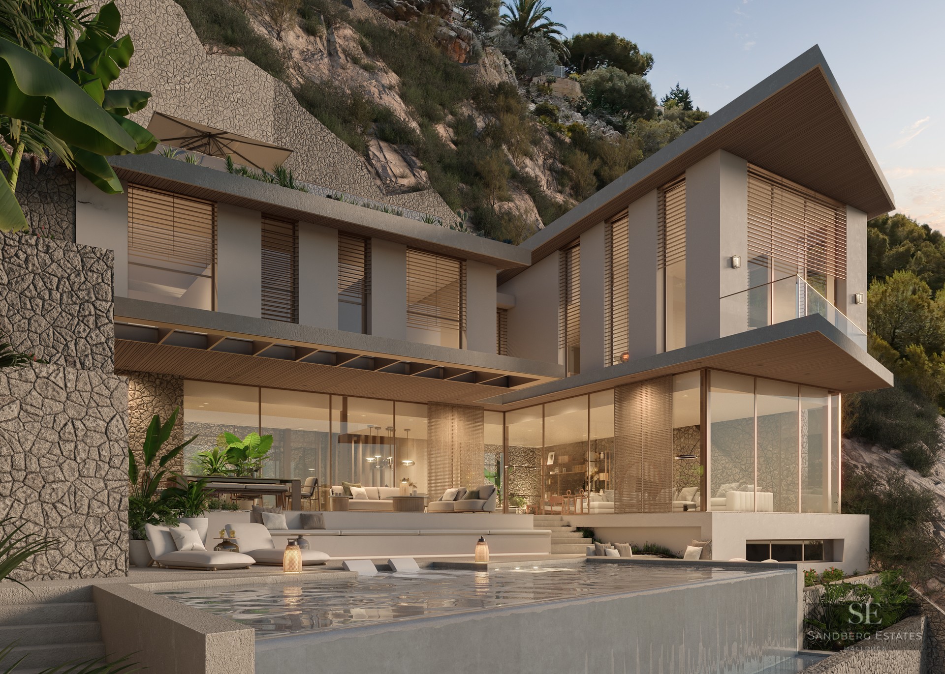 Two-story modern villa with stone walls, floor-to-ceiling glass windows, and an infinity pool at dusk.