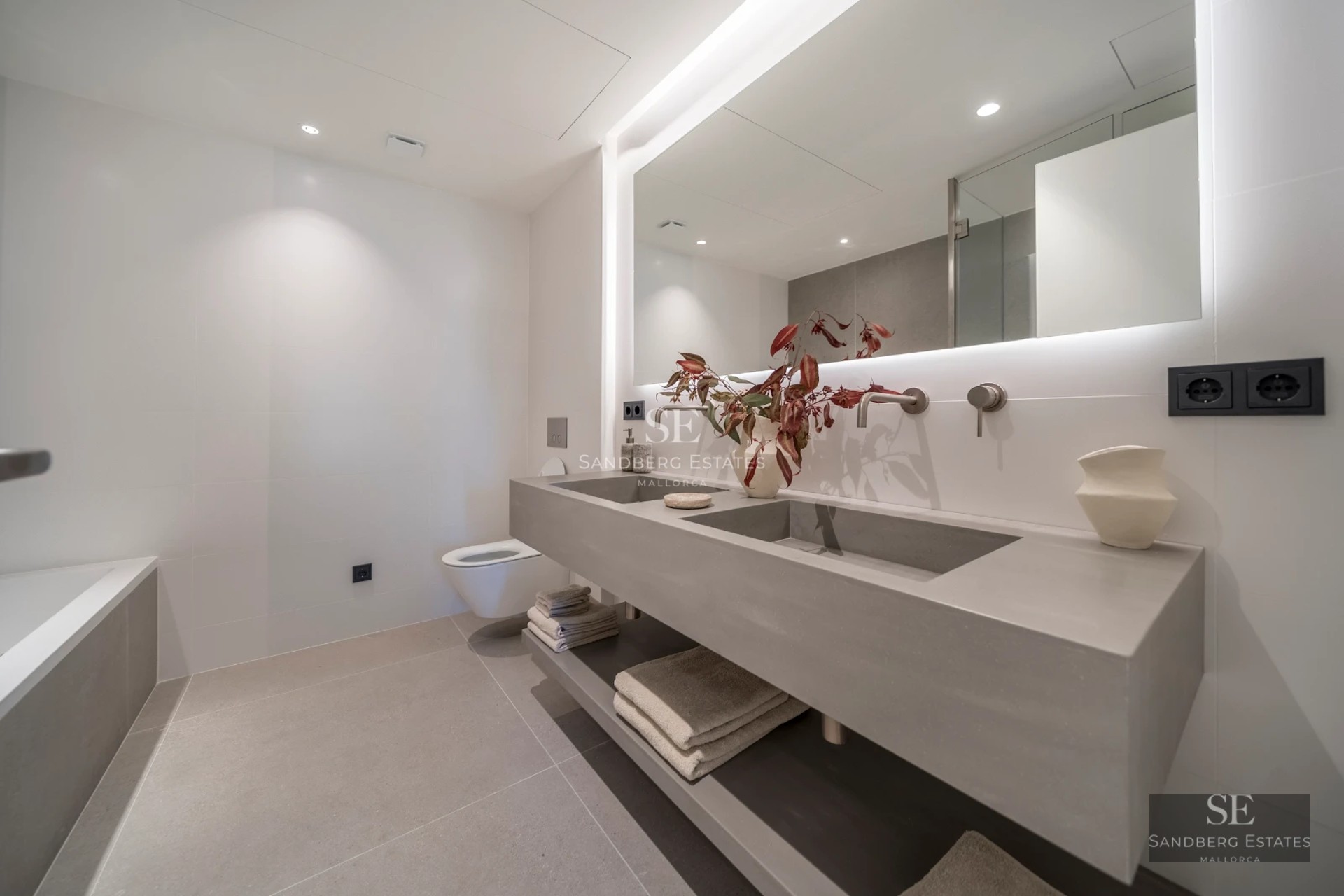 Infinity pool with sea view, surrounded by light-colored tiles and lush vegetation. Modern and elegant design.