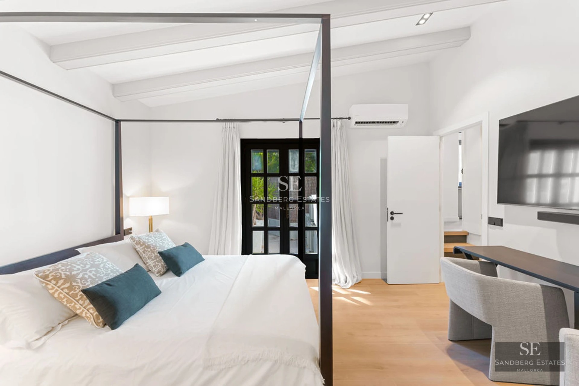 View of a luxurious pool with loungers and umbrellas, surrounded by gardens and a modern house in the background.