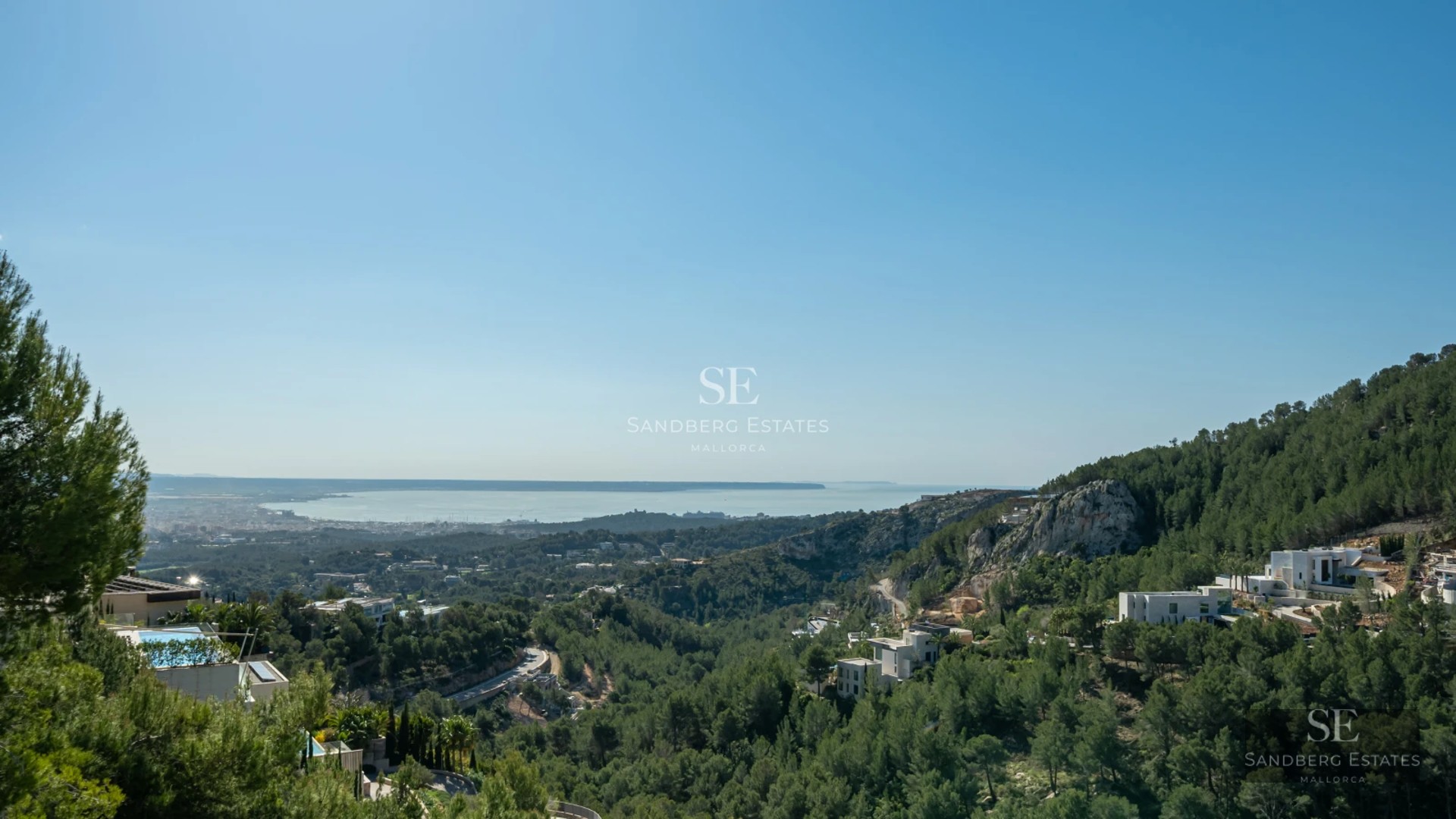 Spacious living room with fireplace, large windows and access to a terrace with a pool. Modern, bright, and elegant interior.