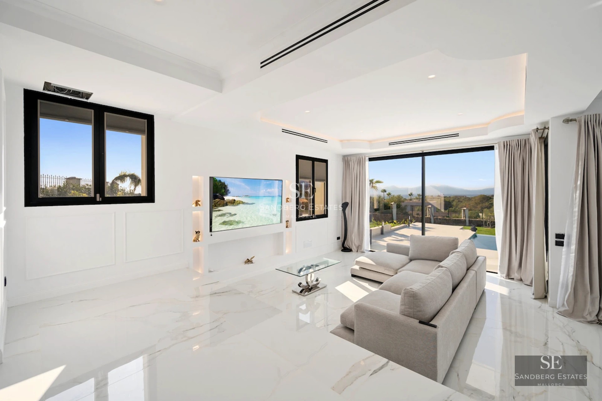 Spacious balcony with panoramic sea views. Glass railing, modern outdoor furniture, wooden floor, and lush vegetation.