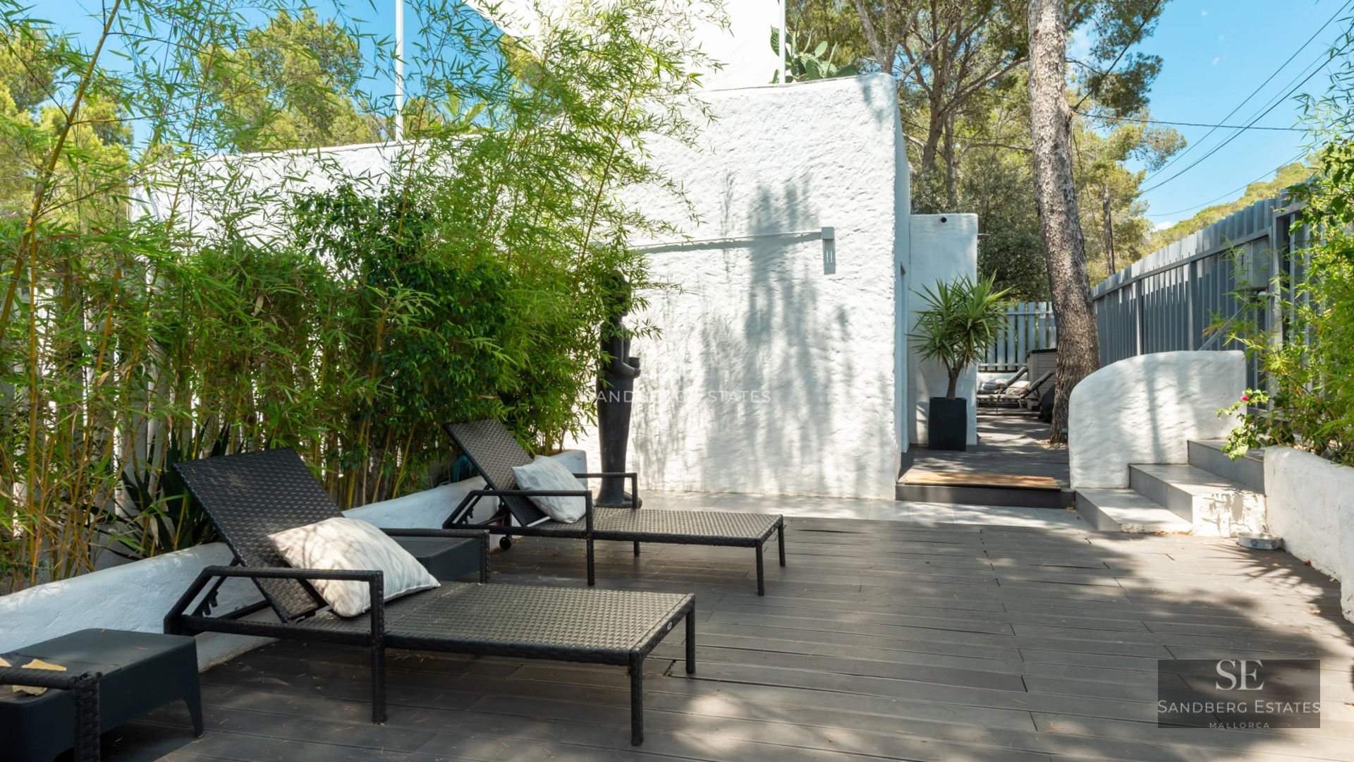 View of modern villa featuring infinity pool, sun loungers, manicured lawn, and minimalist architecture on a sunny day.