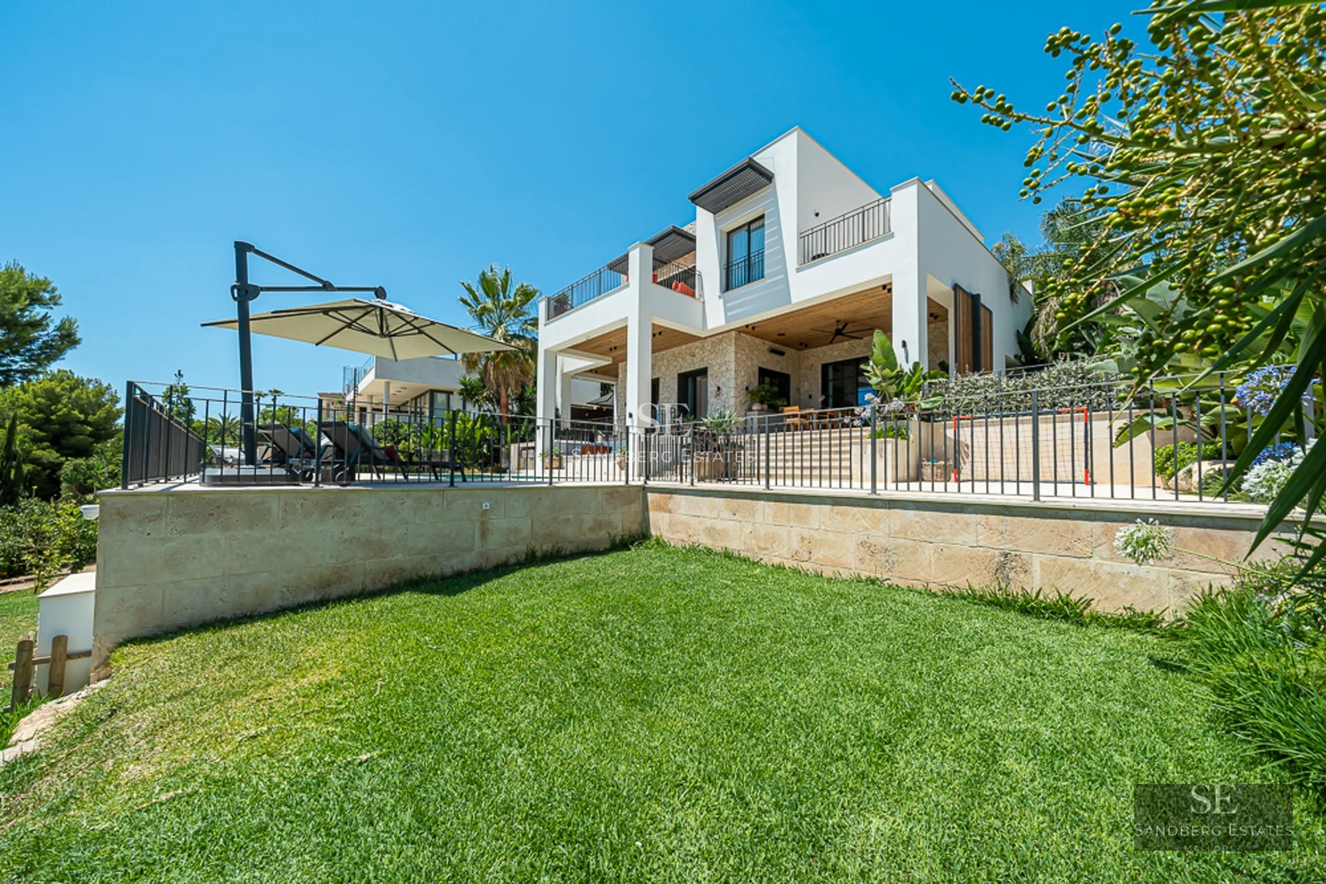 Vue extérieure d'une villa moderne avec piscine à débordement, jardins luxuriants et vastes terrasses. Design minimaliste et élégant.