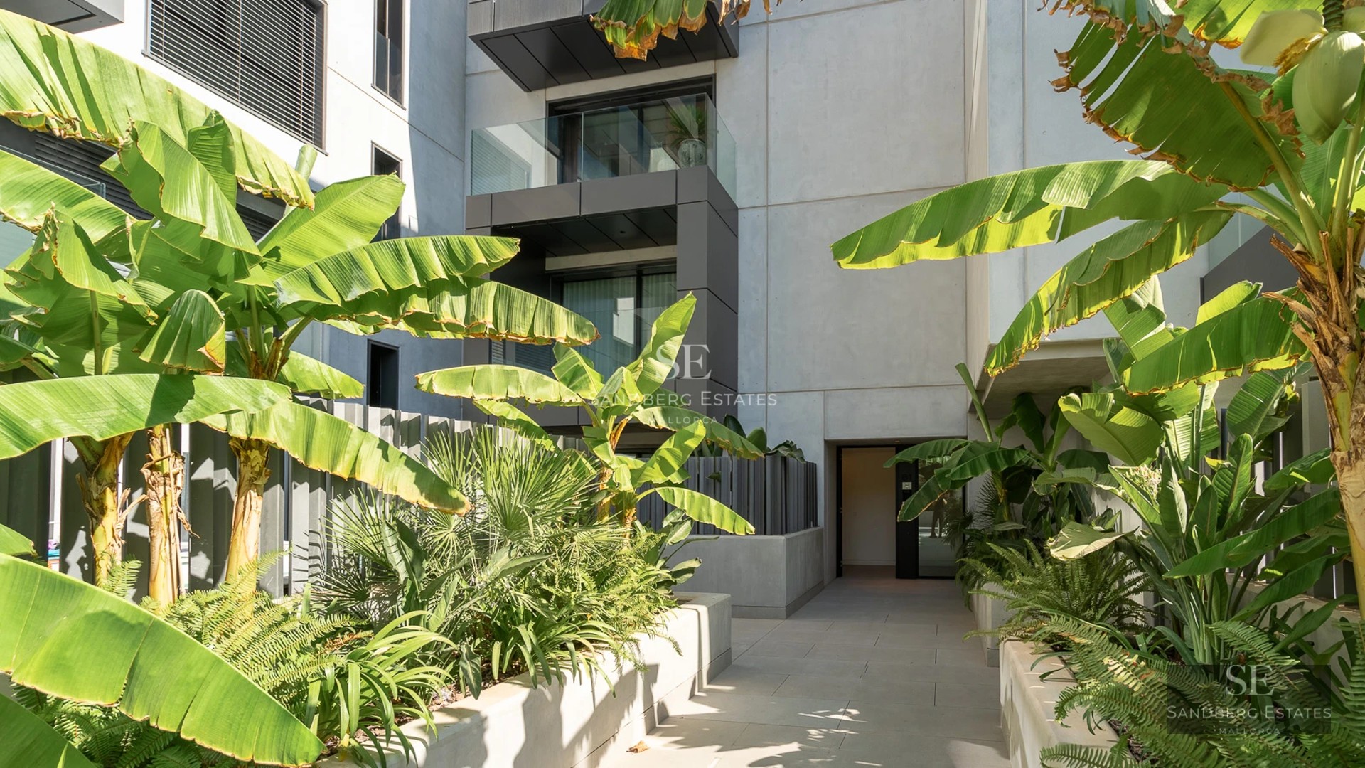View of a modern villa featuring an infinity pool, lush gardens, and panoramic sea views. Minimalist and elegant architectural design.