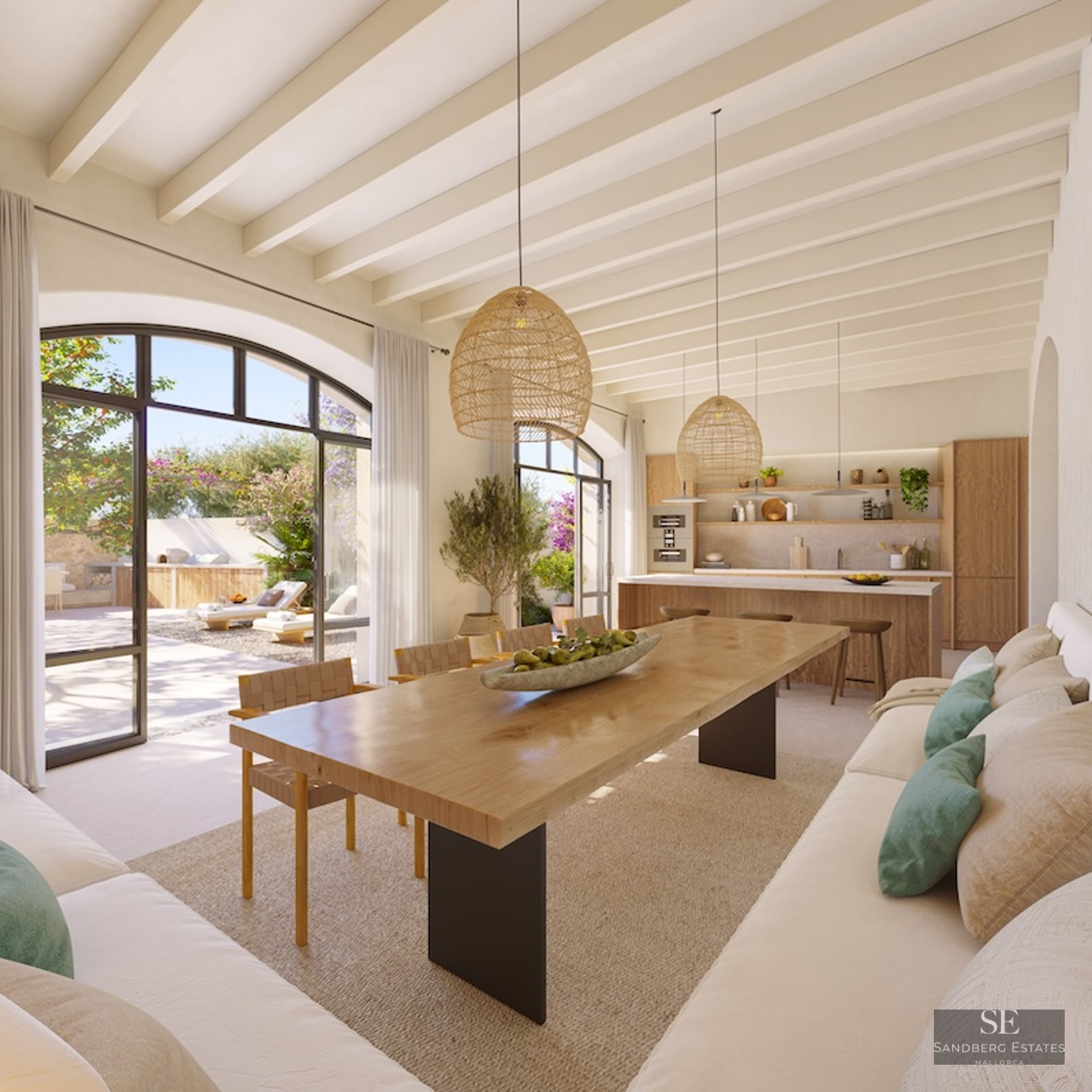 Spacious dining area with a long wooden table, wicker lamps, and large arched windows leading to a sunny terrace.
