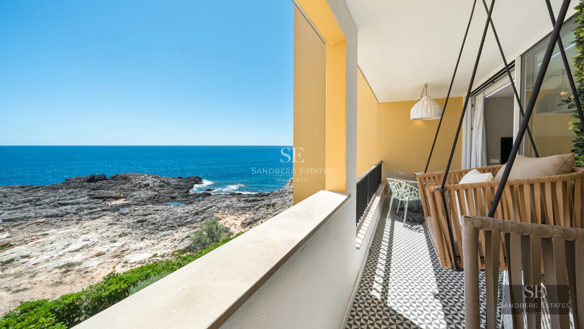 Spacious living room with floor-to-ceiling windows, natural light, wood flooring and sea view. Modern sofa and minimalist decor.