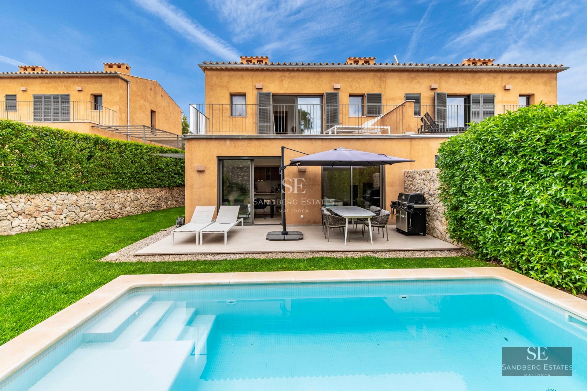 View of a modern villa with infinity pool, lounge chairs, lush garden, and panoramic views. Minimalist architecture and luxury finishes.