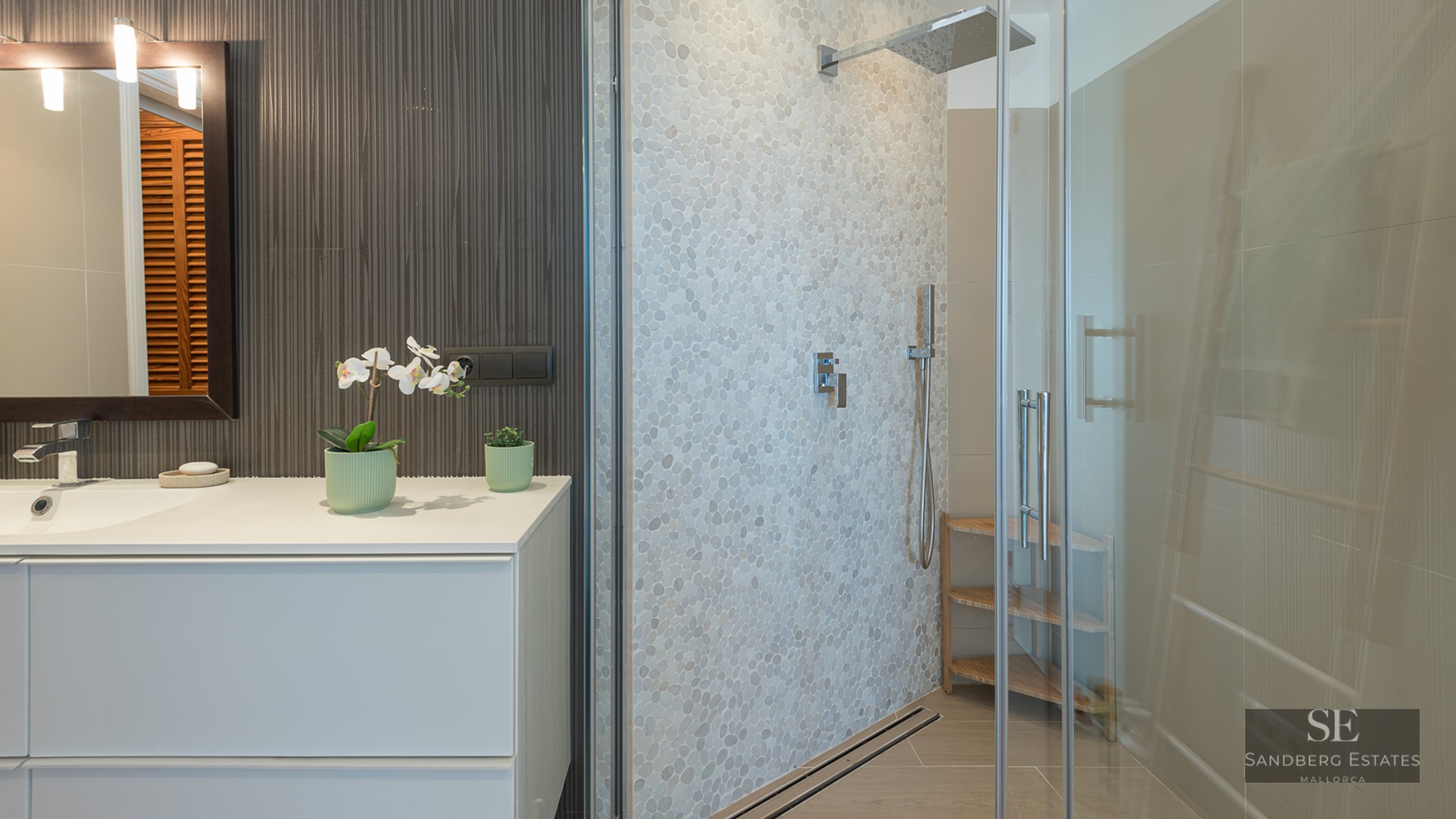 Contemporary bathroom featuring a white vanity and a walk-in glass shower with a textured pebble wall.