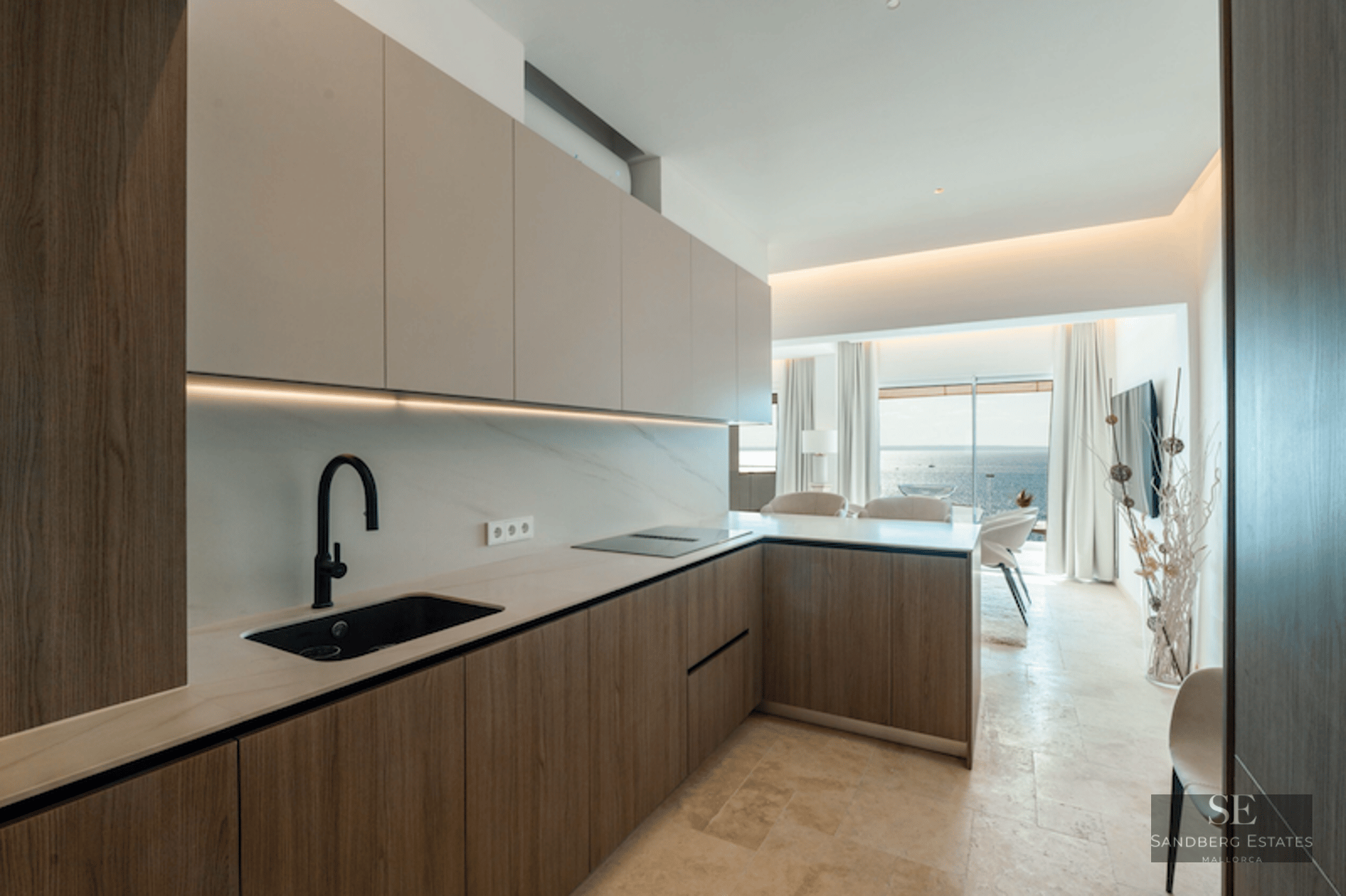 Minimalist kitchen with wood cabinetry, marble backsplash, and a panoramic sea view in the background.