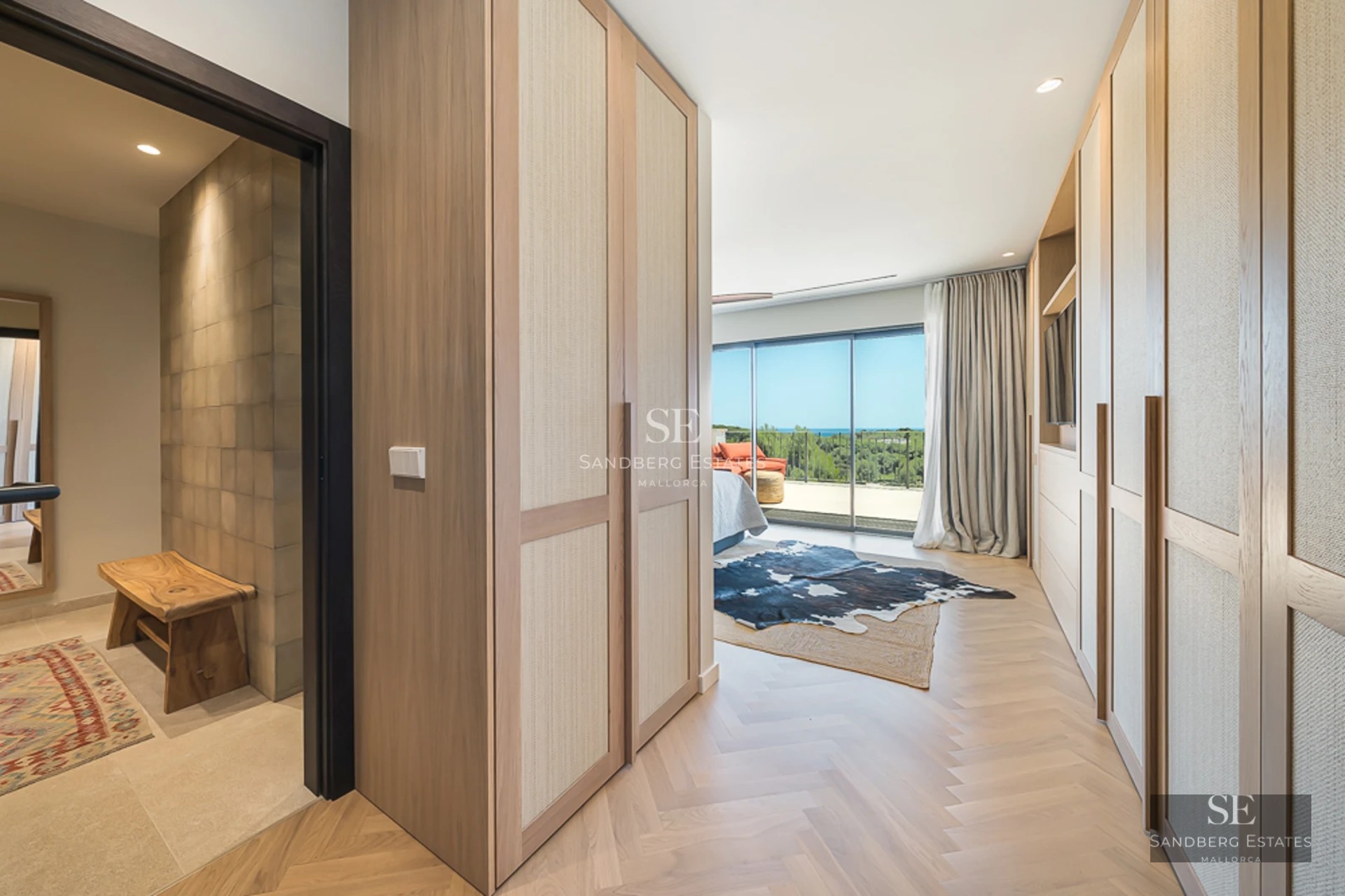 Vaste salon avec grandes baies vitrées, parquet clair, cheminée moderne et mobilier design minimaliste. Lumière naturelle abondante.