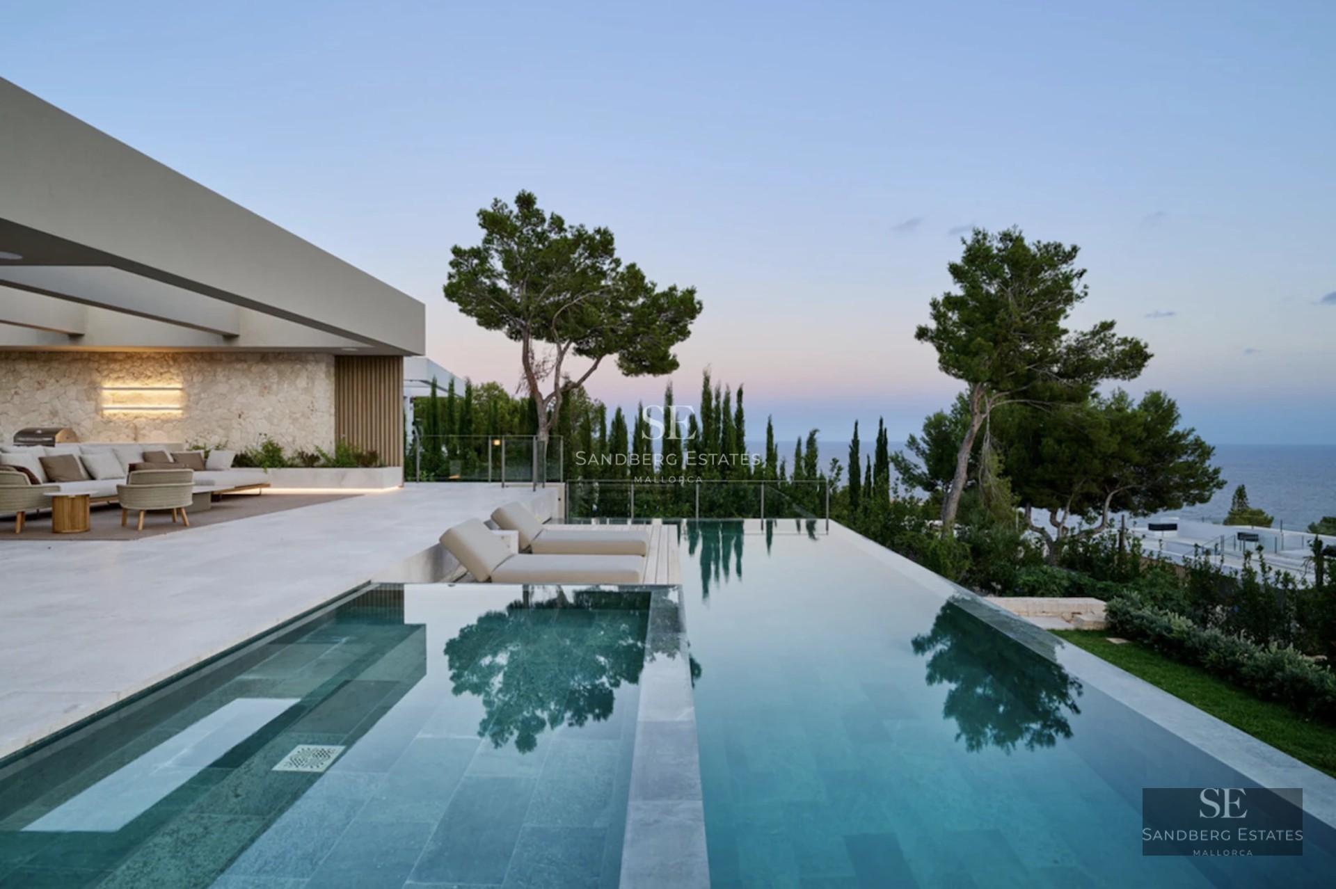 Spacious living room with large windows, modern furniture, light wood floors and access to a balcony with stunning sea views.