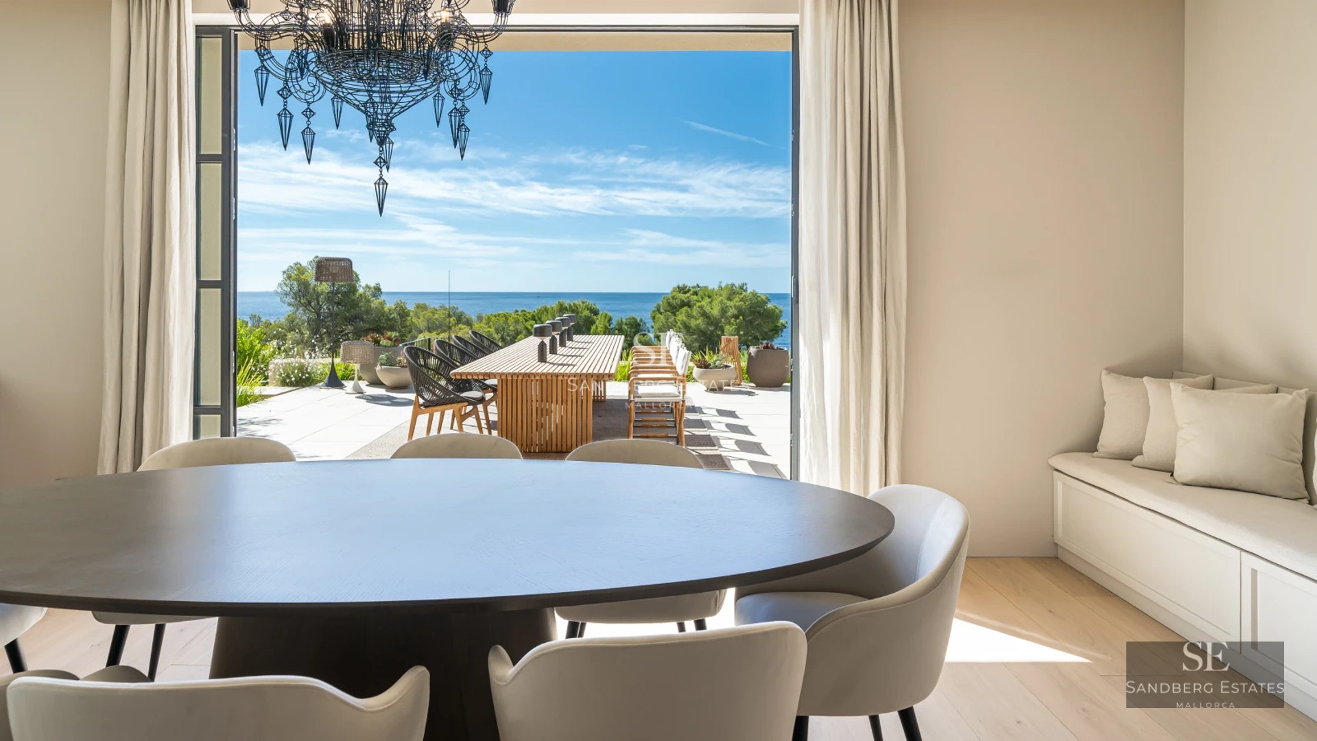 View of poolside garden surrounded by lawn, sun loungers, and a modern house with large windows. Clear sky.