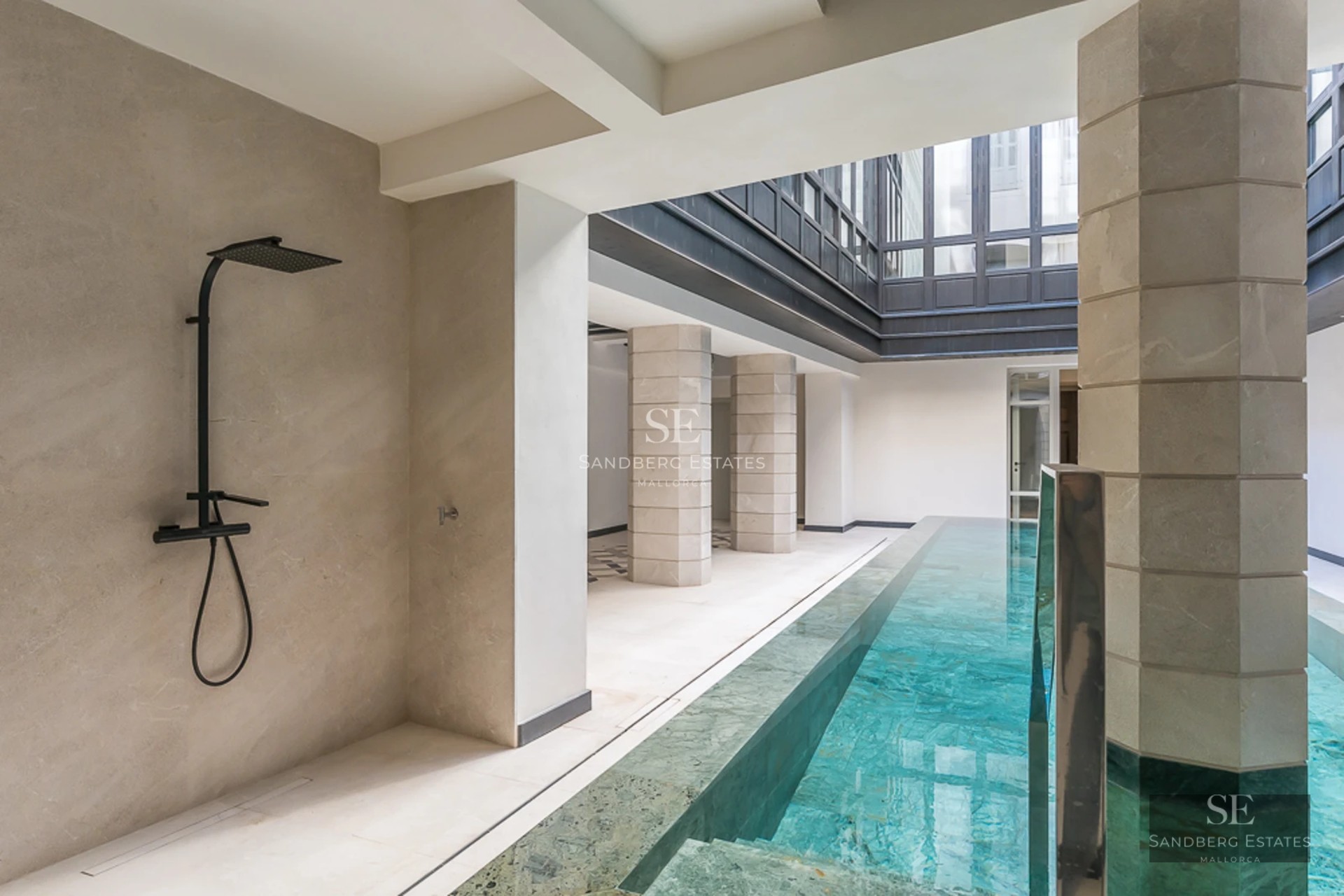 Expansive pool deck surrounded by lush greenery. Modern design with comfortable outdoor furniture. Ambient lighting and relaxing views.