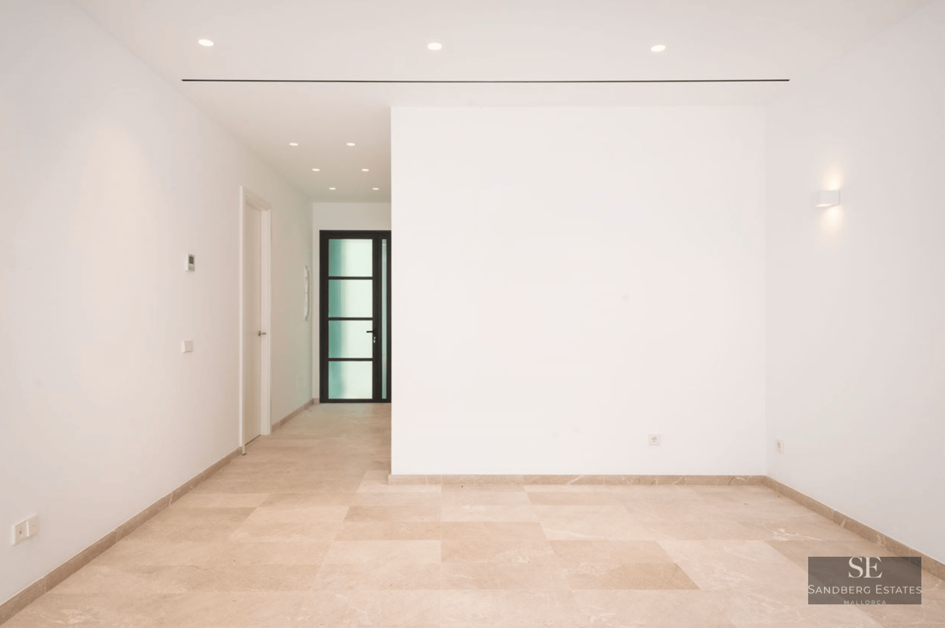 A bright, empty minimalist entrance hall with polished cream marble floors, white walls, and recessed ceiling lighting.