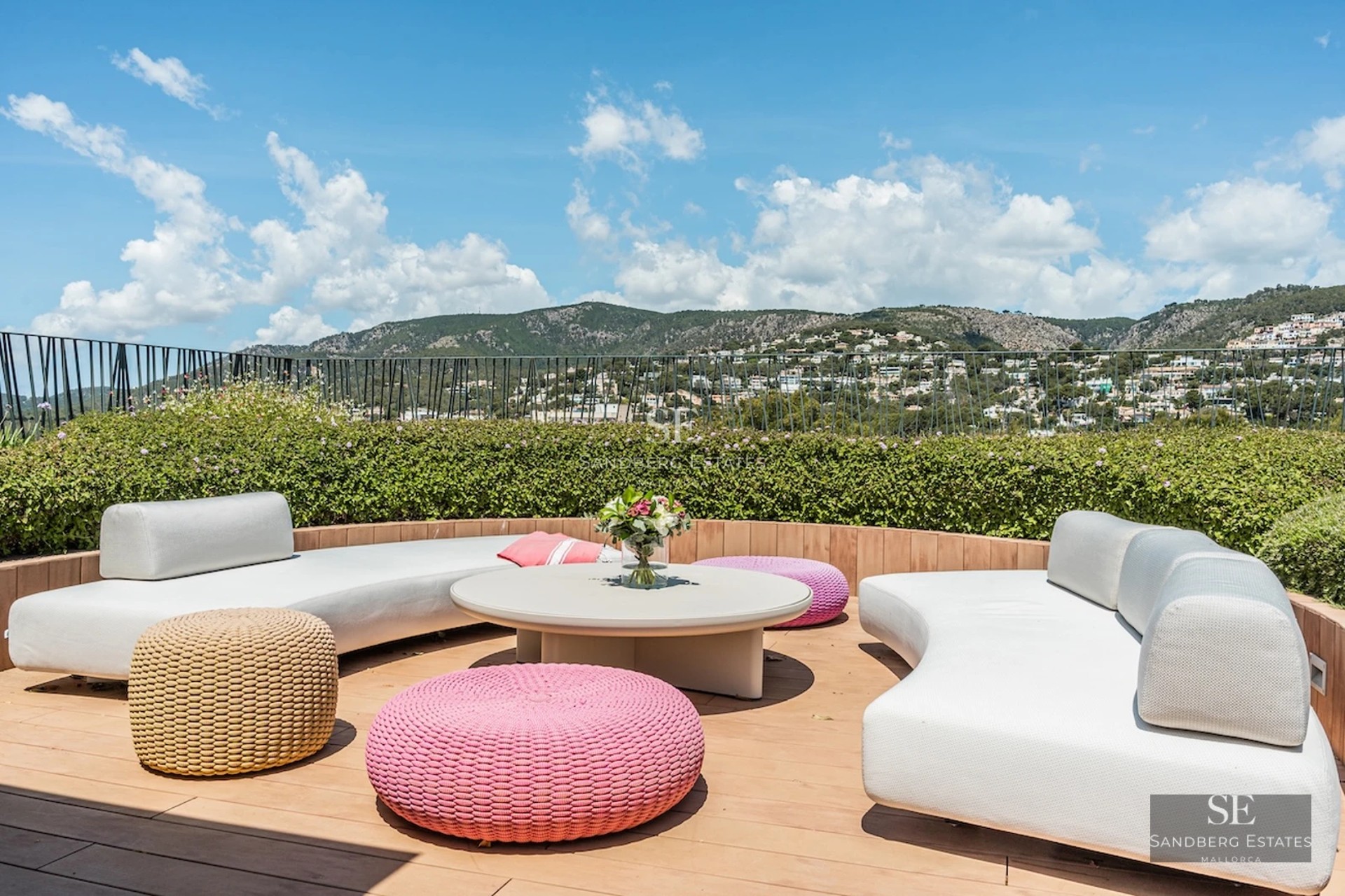 View of an infinity pool bordered by lawn and a modern villa featuring large windows and elegant outdoor furniture.